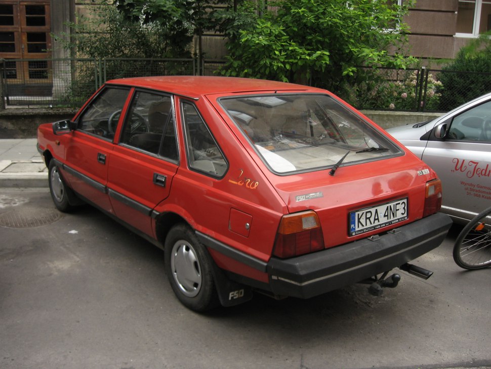 Angular rear window and black bumper of a red hatchback