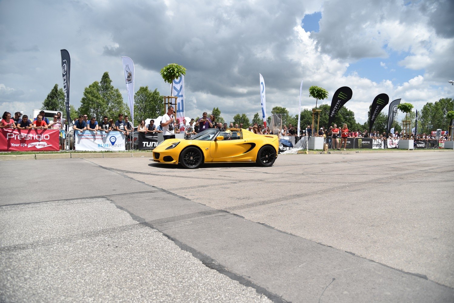 Yellow convertible sports car with black wheels on paved area at car event