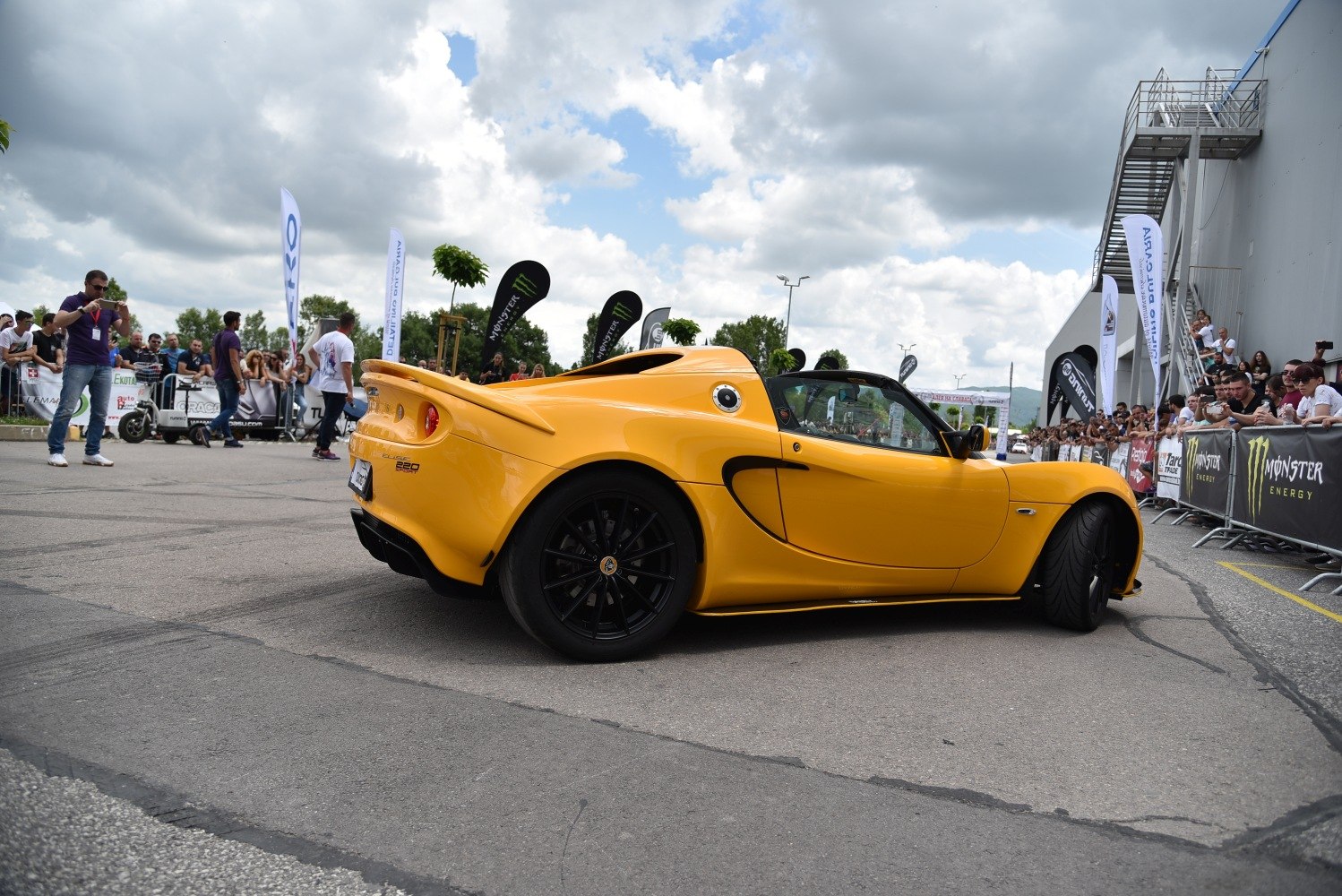 Yellow sports coupe showing side and rear view with black rims
