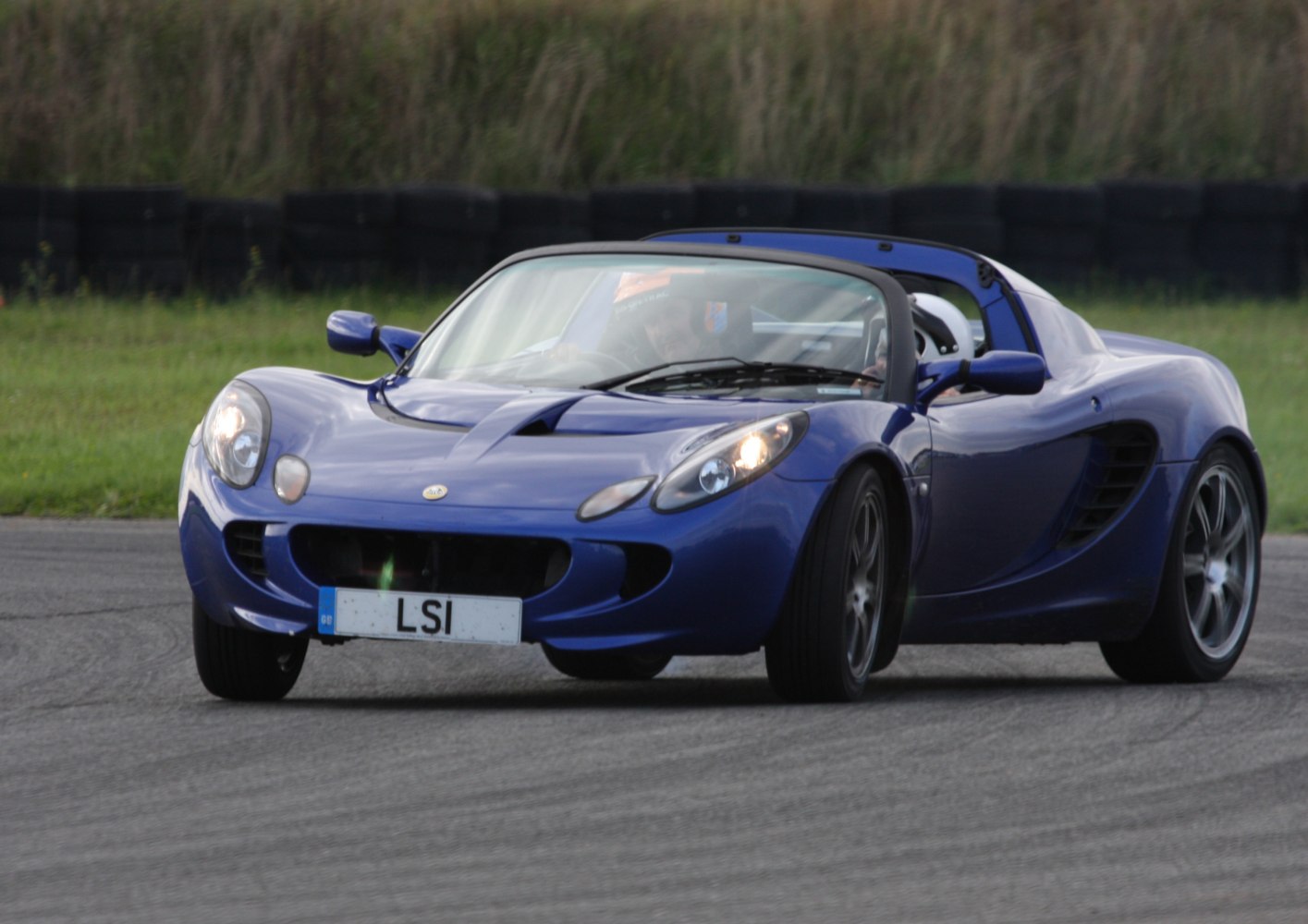 Blue lightweight open-top sports car with aerodynamic design on a racetrack