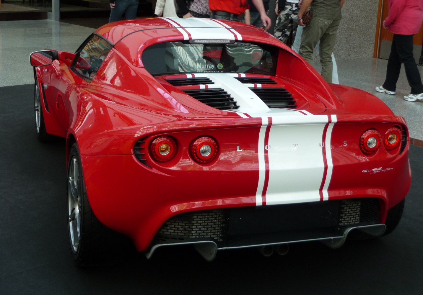 Red Lotus Elise with white racing stripes and dual round taillights