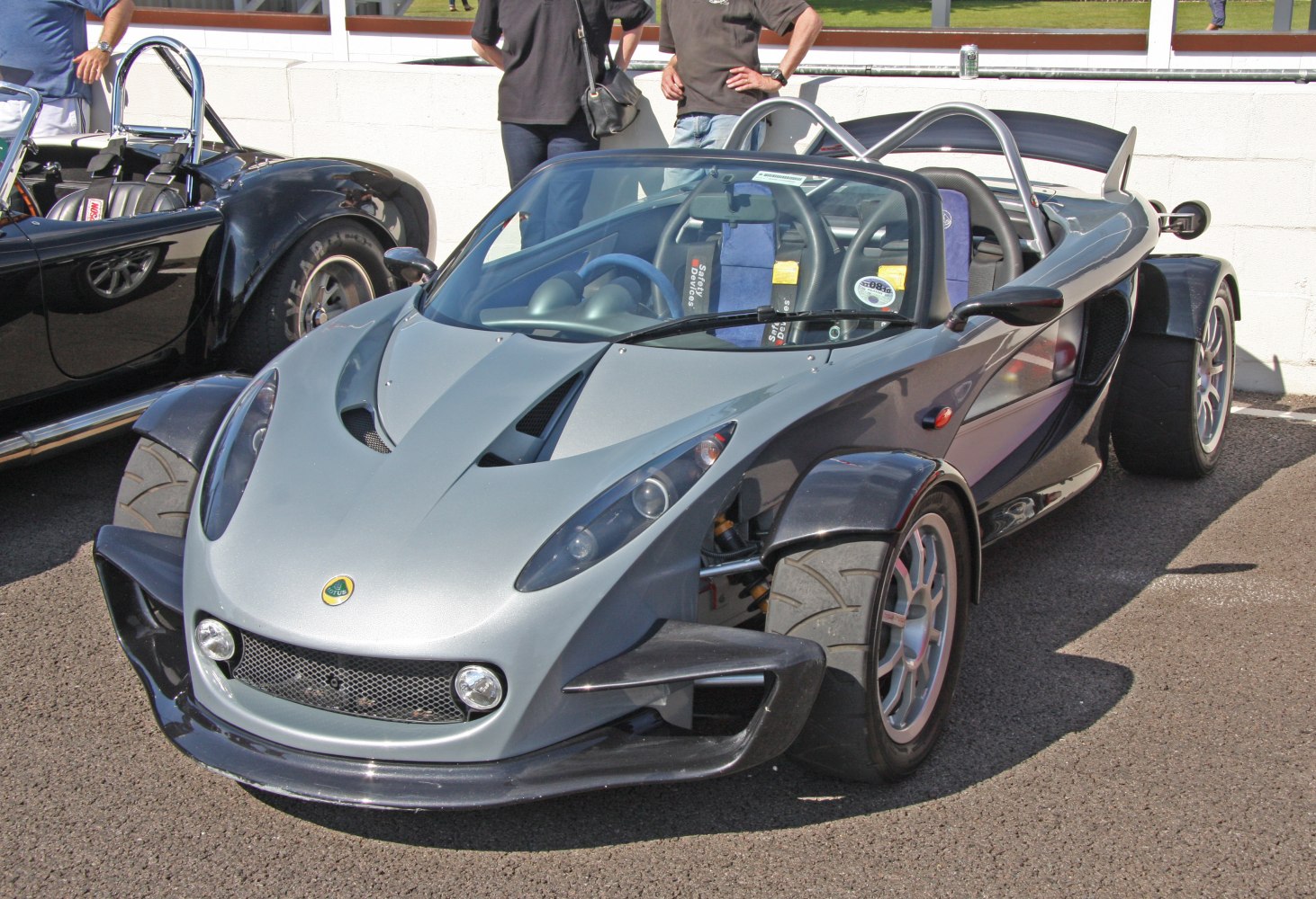 Front and side view of a lightweight sports roadster with exposed front wheels and aerodynamic body.