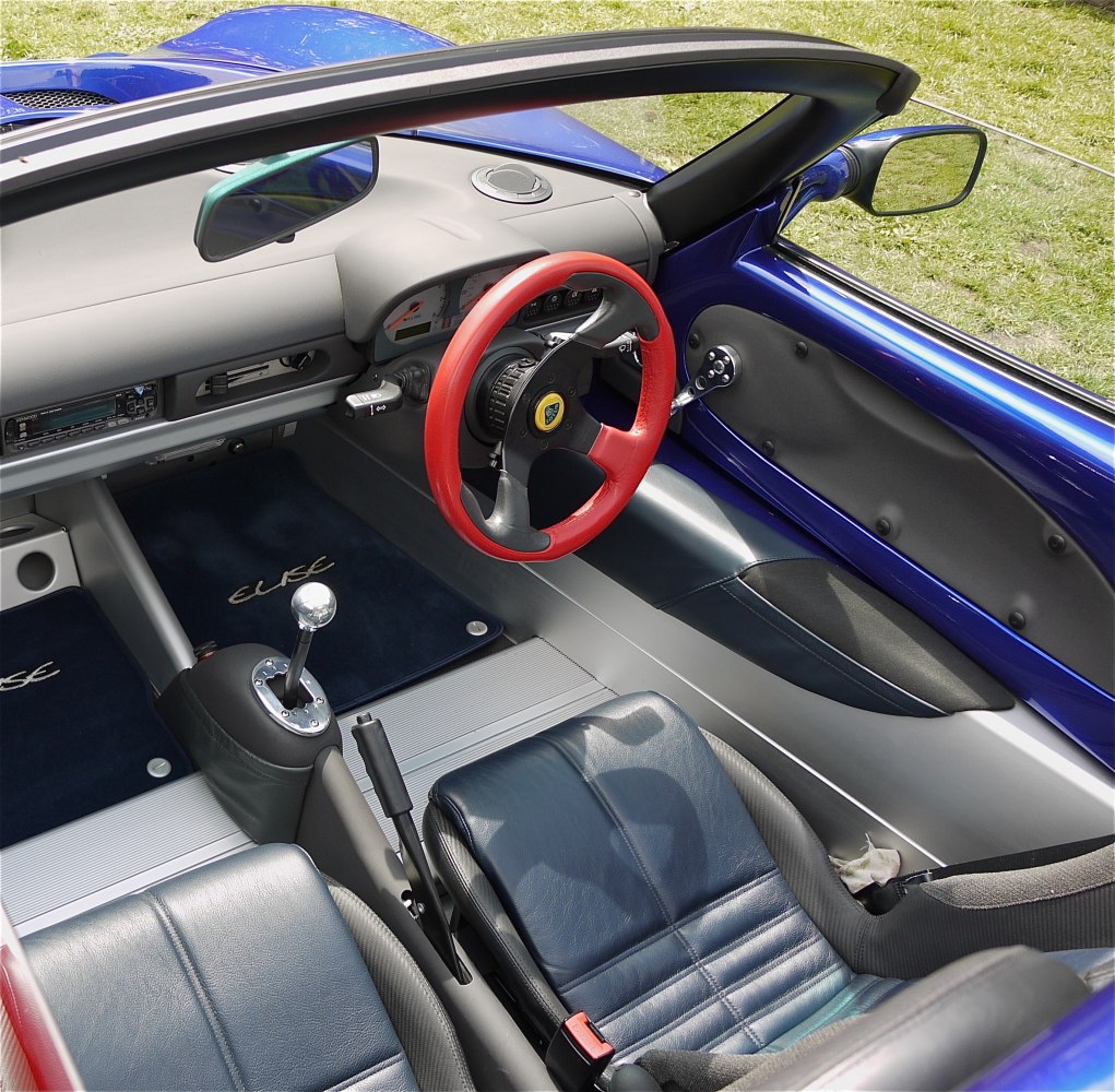 Sporty two-seater interior with red steering wheel and manual gear shift