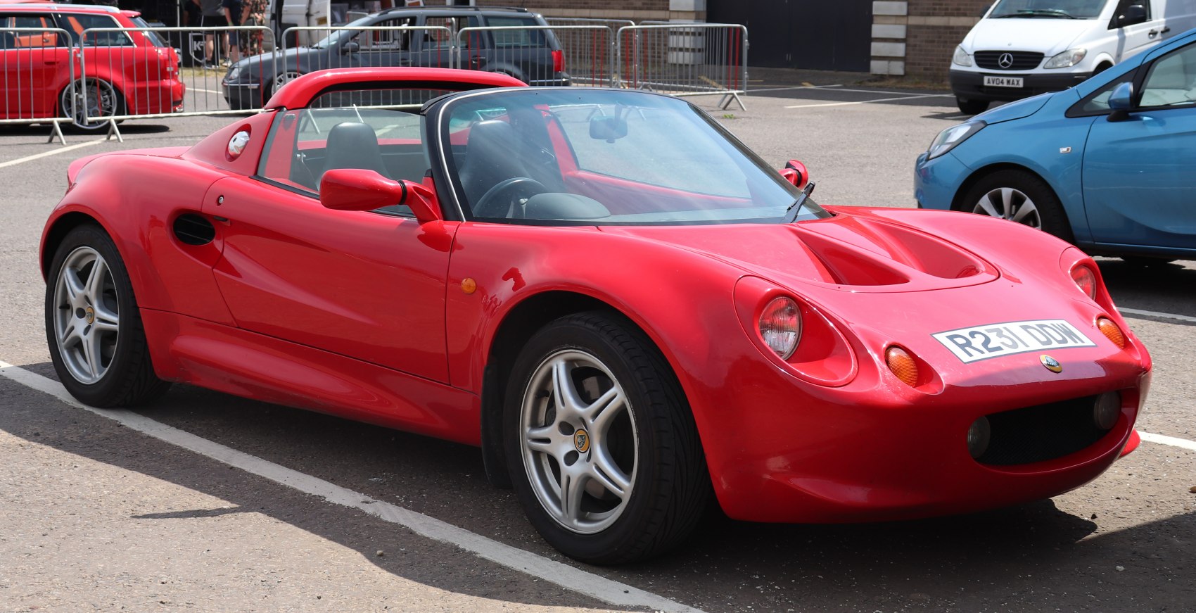 Red convertible sports car with rounded headlights and alloy wheels