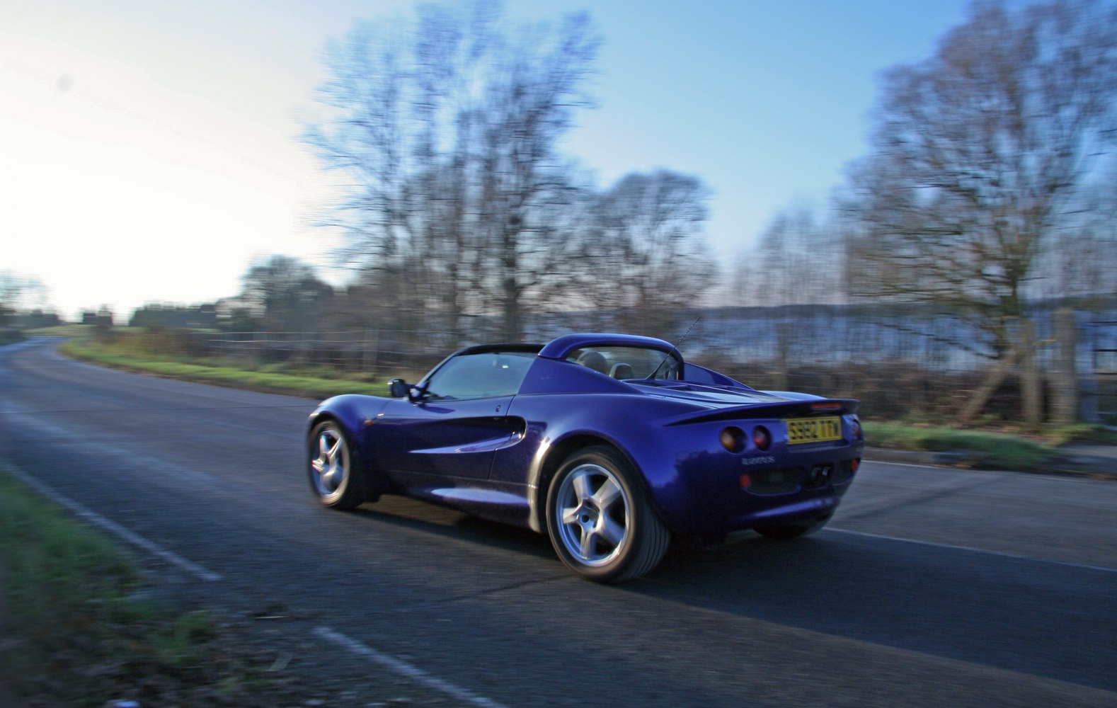 Lightweight sports car with curvy aerodynamic rear and alloy wheels in motion on open road