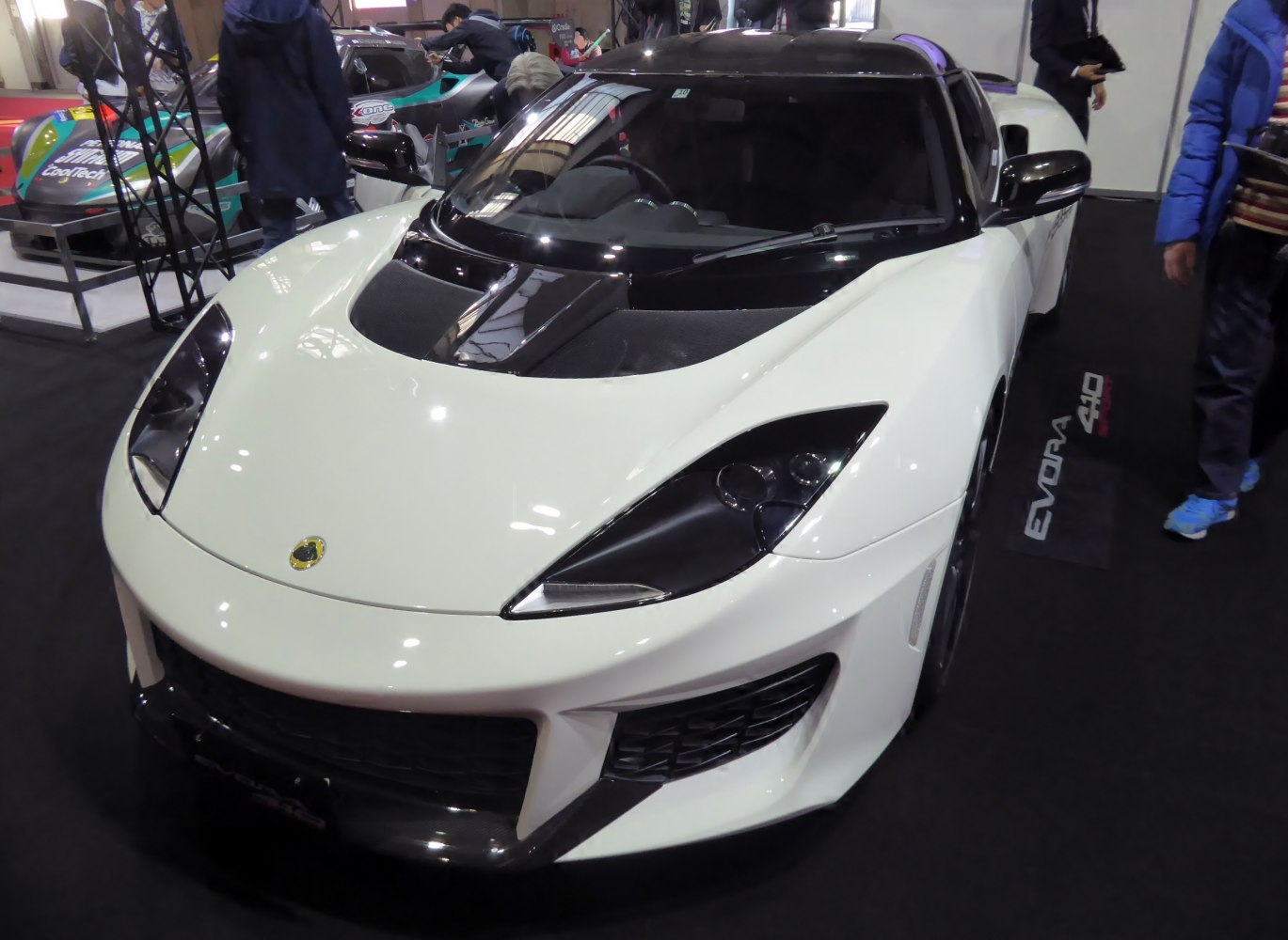 White sports car front with aggressive headlights and vented black hood