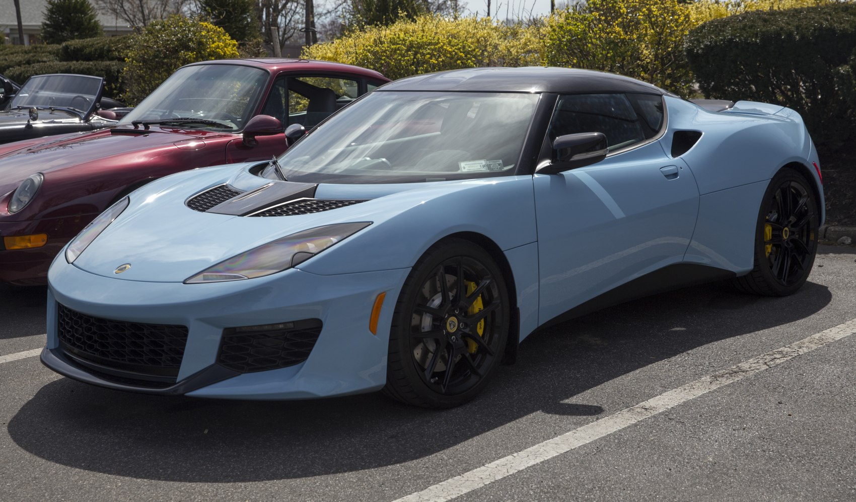 Front side view highlights hood vents, black roof, and yellow brake calipers.