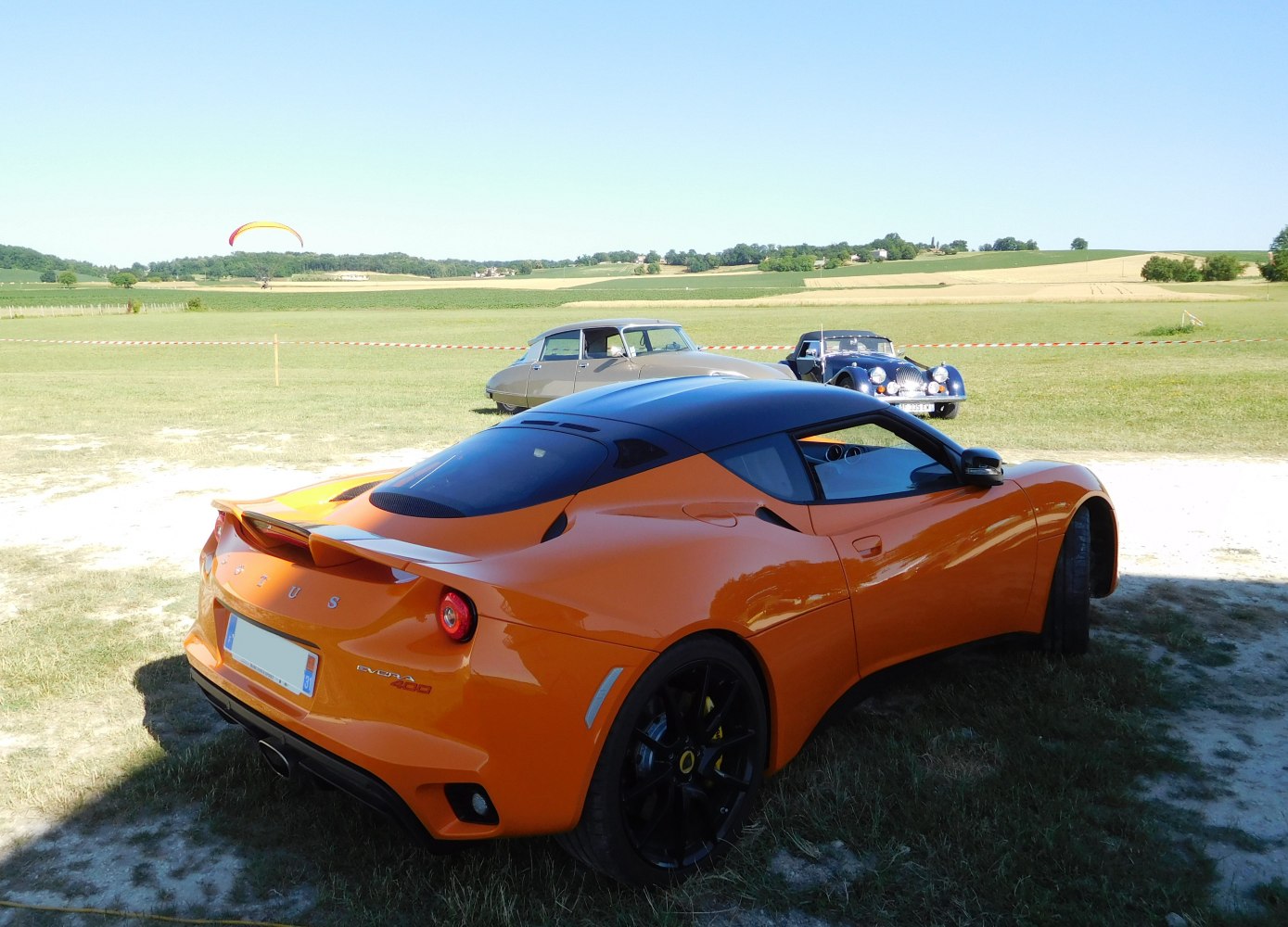 Rear profile of orange sports coupe with black roof and spoiler