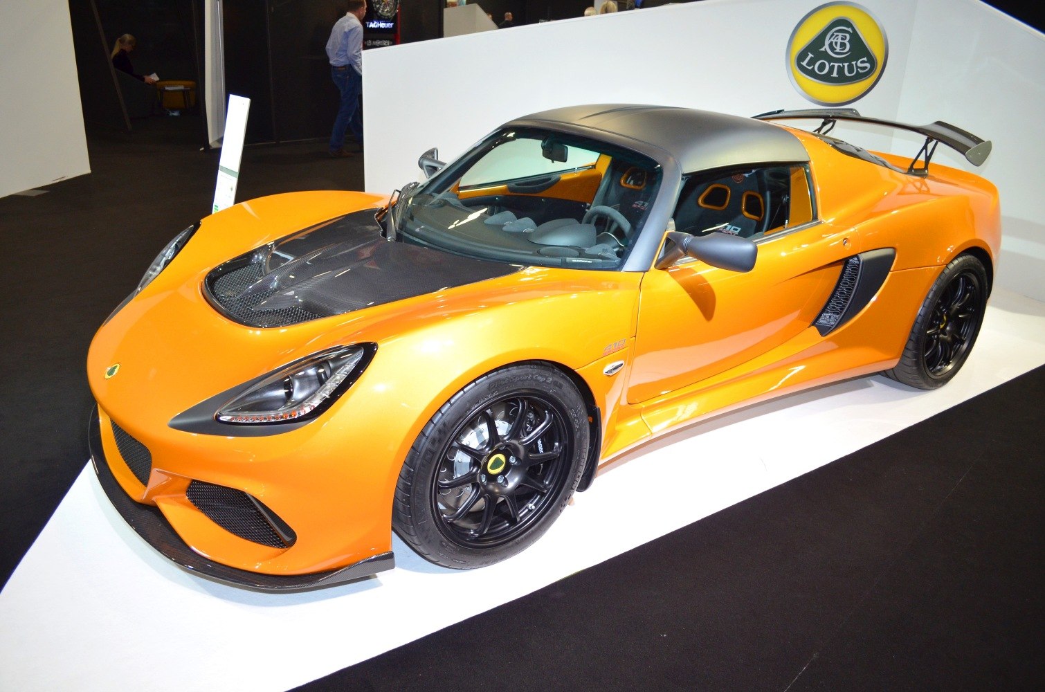 Orange sports coupe with black racing wheels and carbon fiber hood