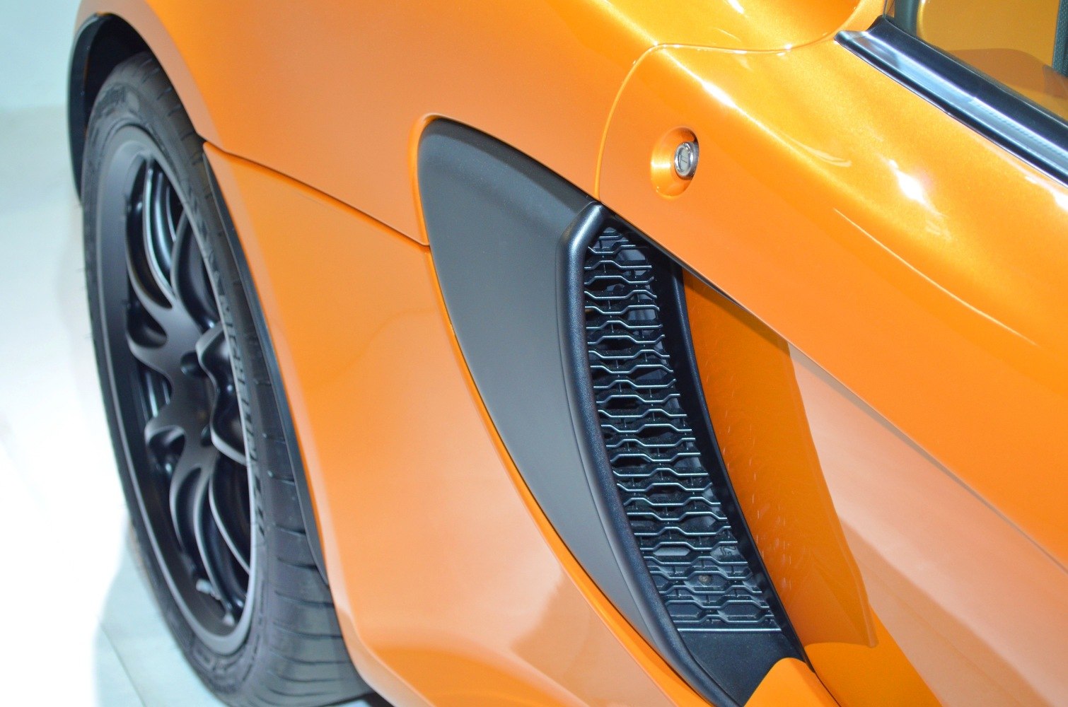 Side air intake vent and rear black wheel on orange sports car