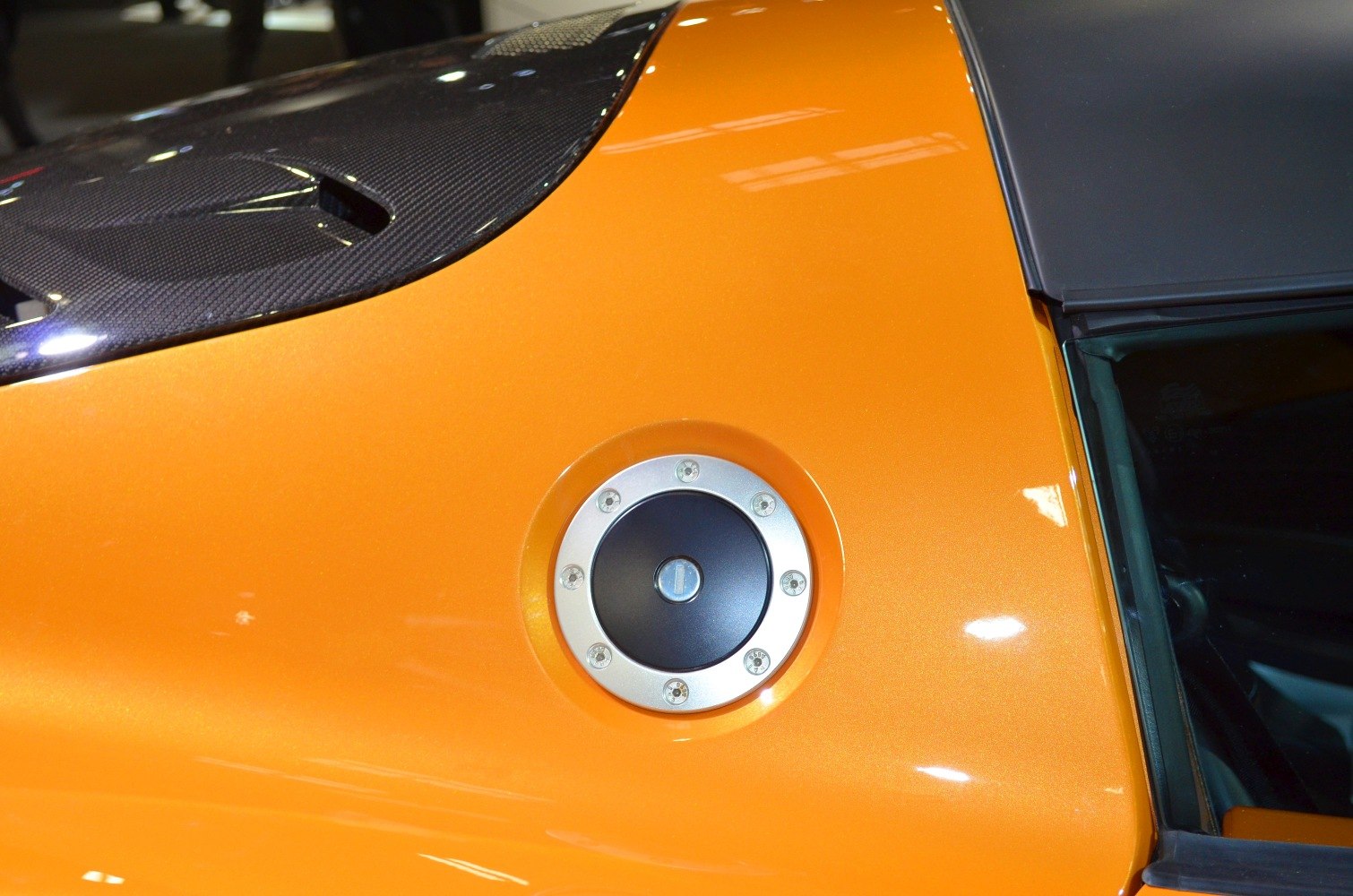 Fuel cap on orange sports car with carbon fiber trim