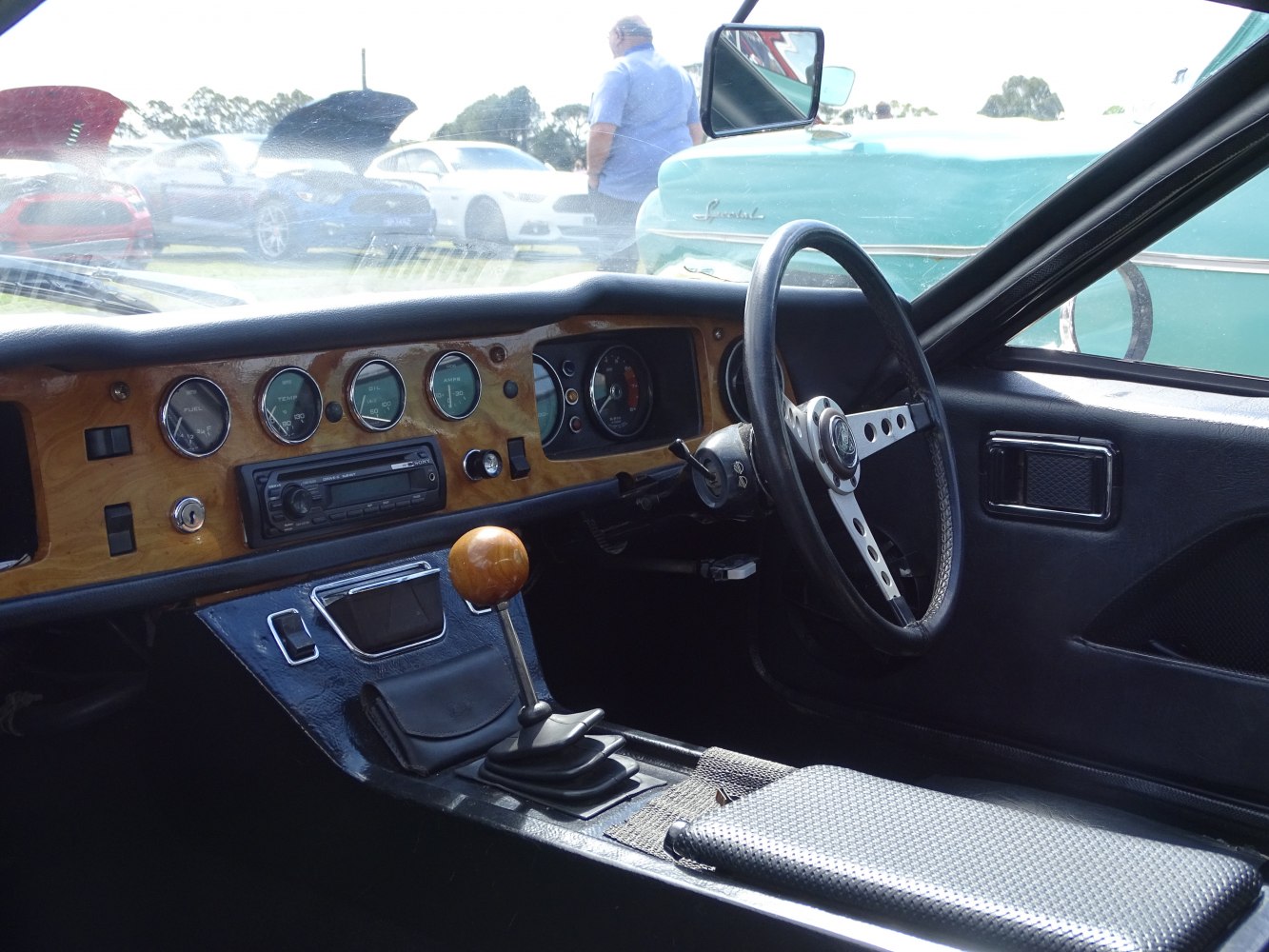 Wooden dashboard with analog gauges and manual gearshift knob inside a vintage sports car
