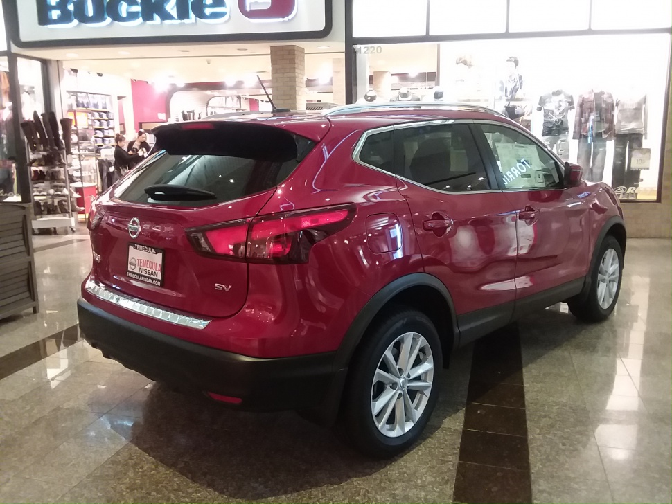 Rear side view of a red compact SUV in showroom