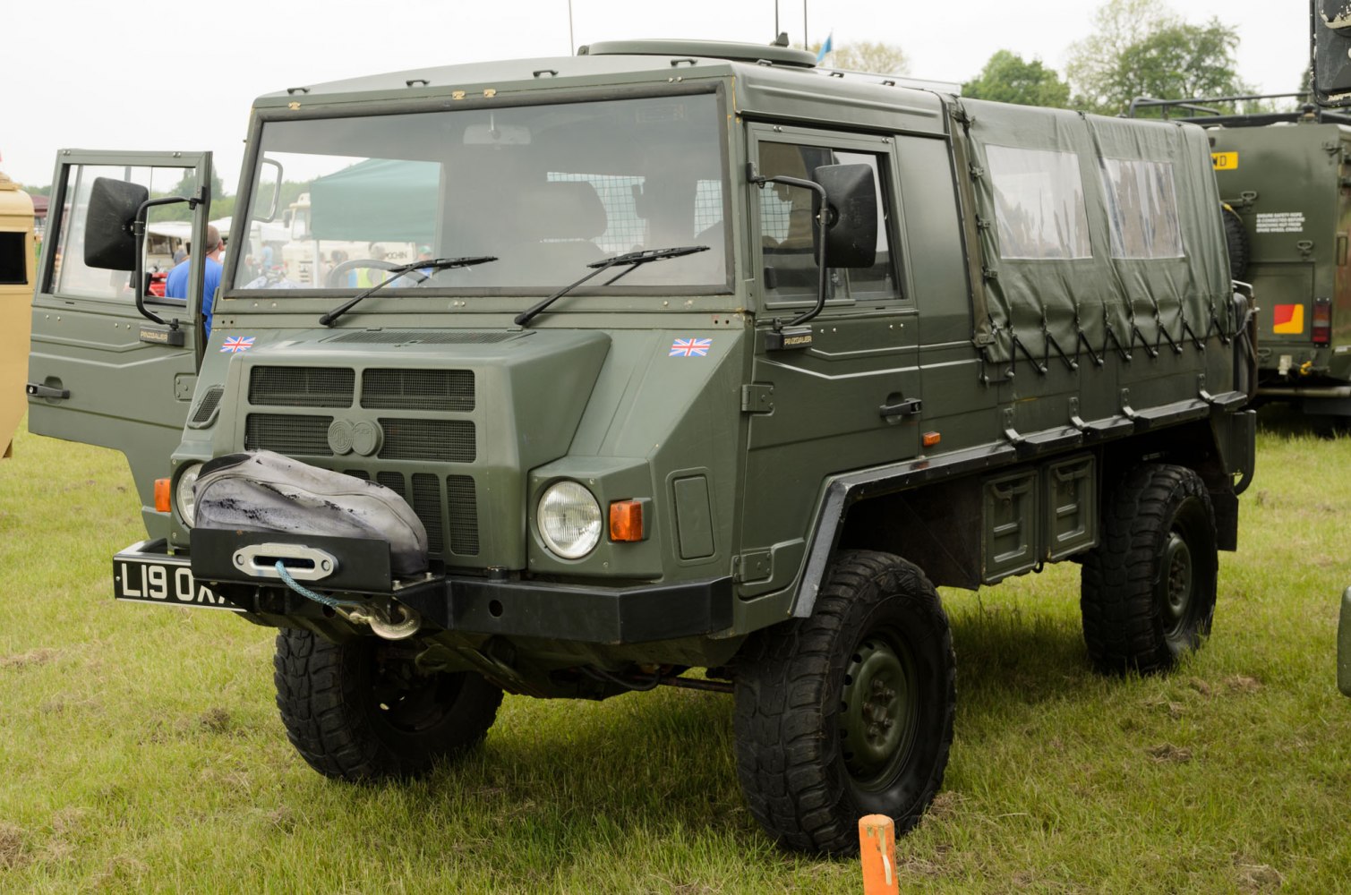 Military-style off-road vehicle with canvas rear bed and large tires