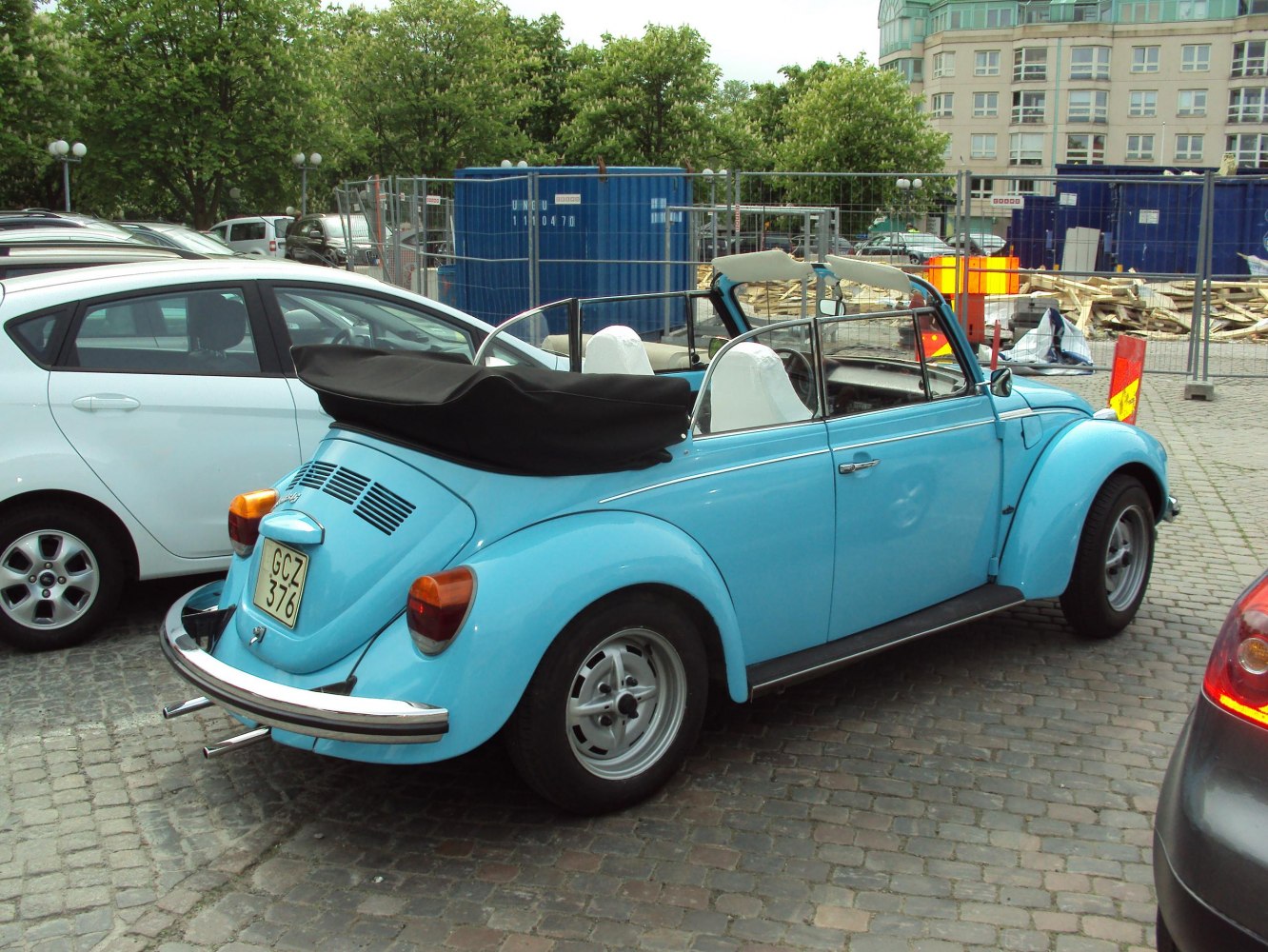 Light blue convertible with folded black soft top and vintage chrome rear bumper