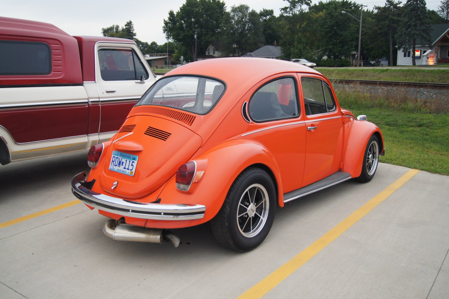 Retro bright orange vintage Volkswagen Kaefer rear view with distinct round rear window and classic wheels