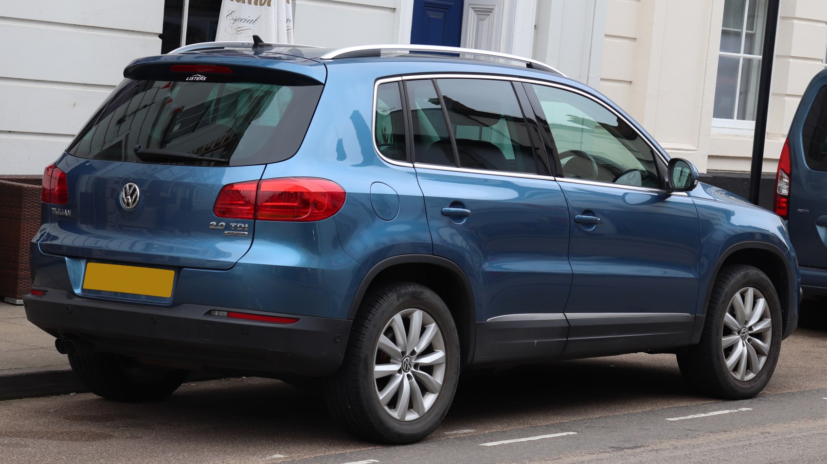 Rear side view of blue compact SUV with roof rails and tinted windows