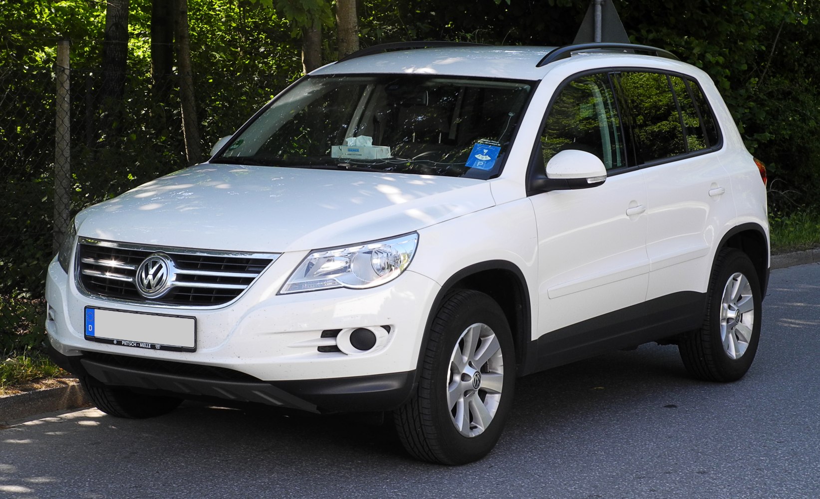 Front side view of a white SUV with alloy wheels and roof rails.