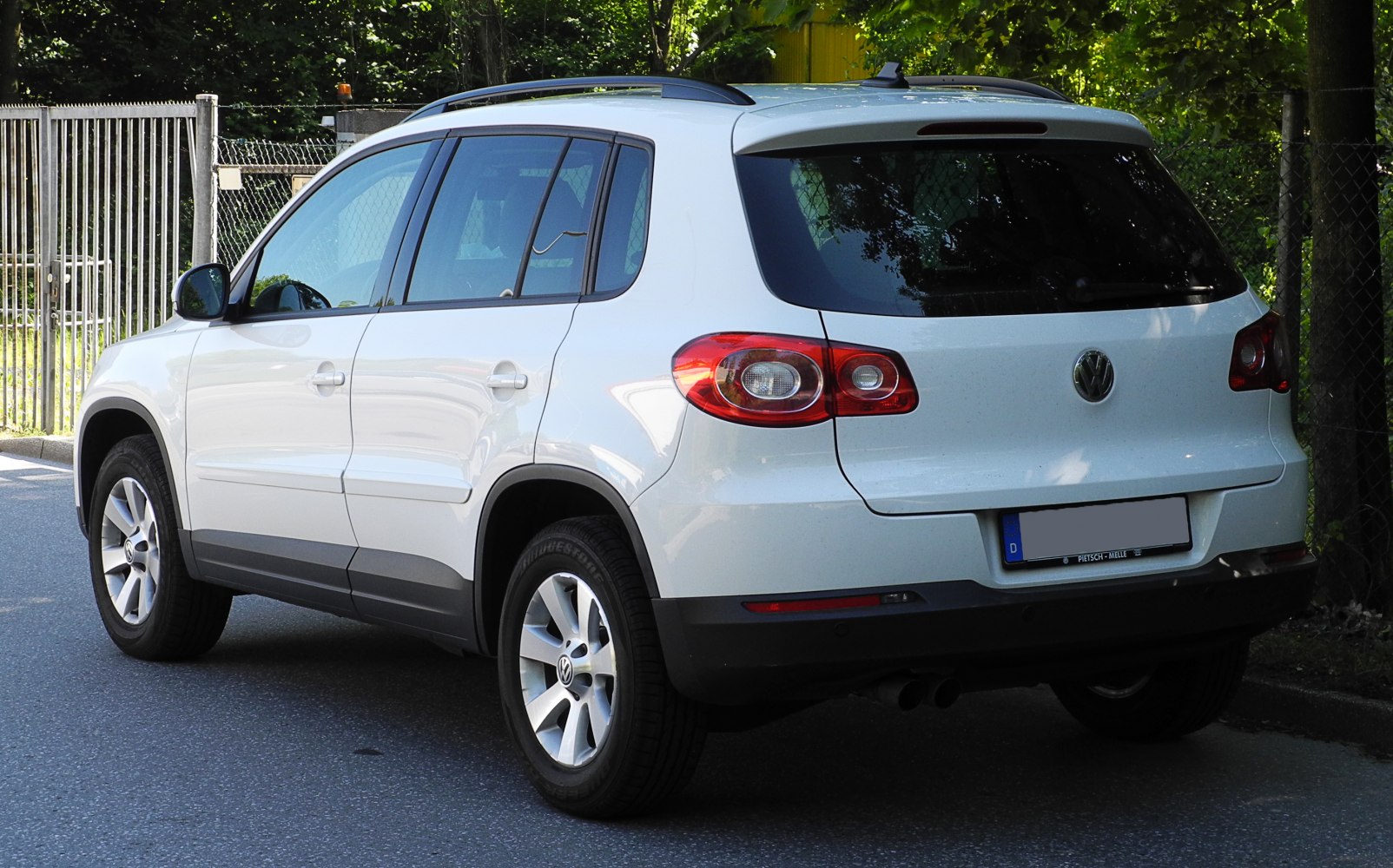 Rear-side view of white compact SUV with alloy wheels and roof rails