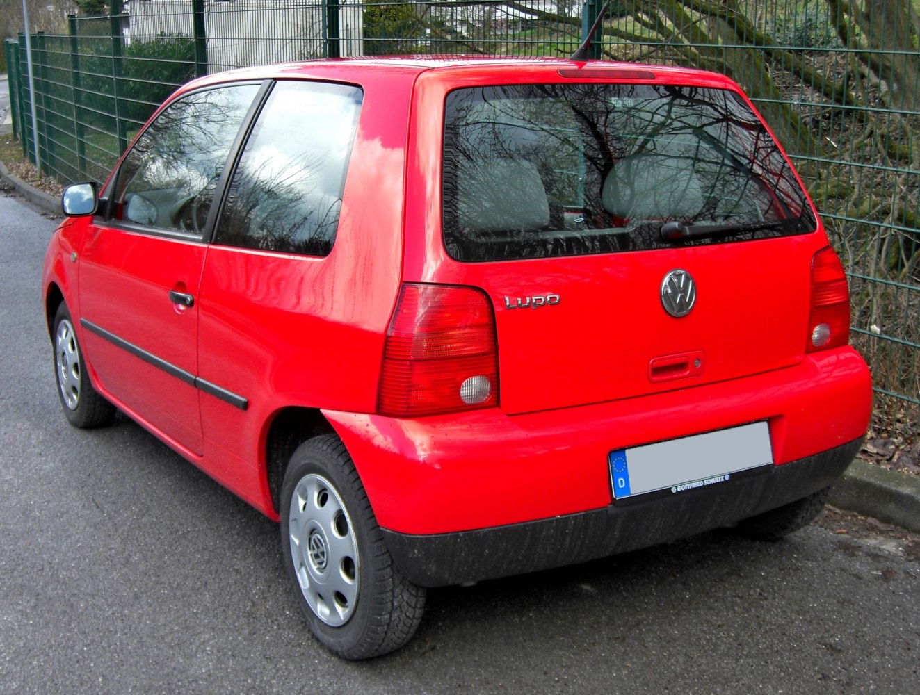 Rear-side view of red compact hatchback with tail lights and rear window
