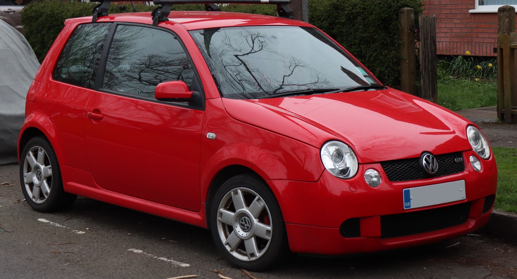 Red compact hatchback front side with round headlights and alloy wheels