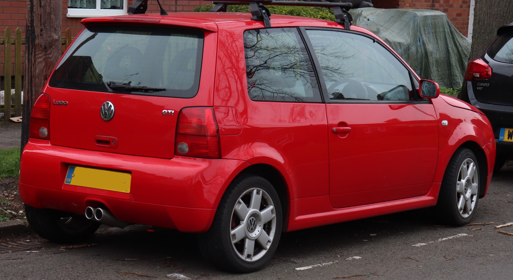 Red compact hatchback rear side with dual exhaust and alloy wheels