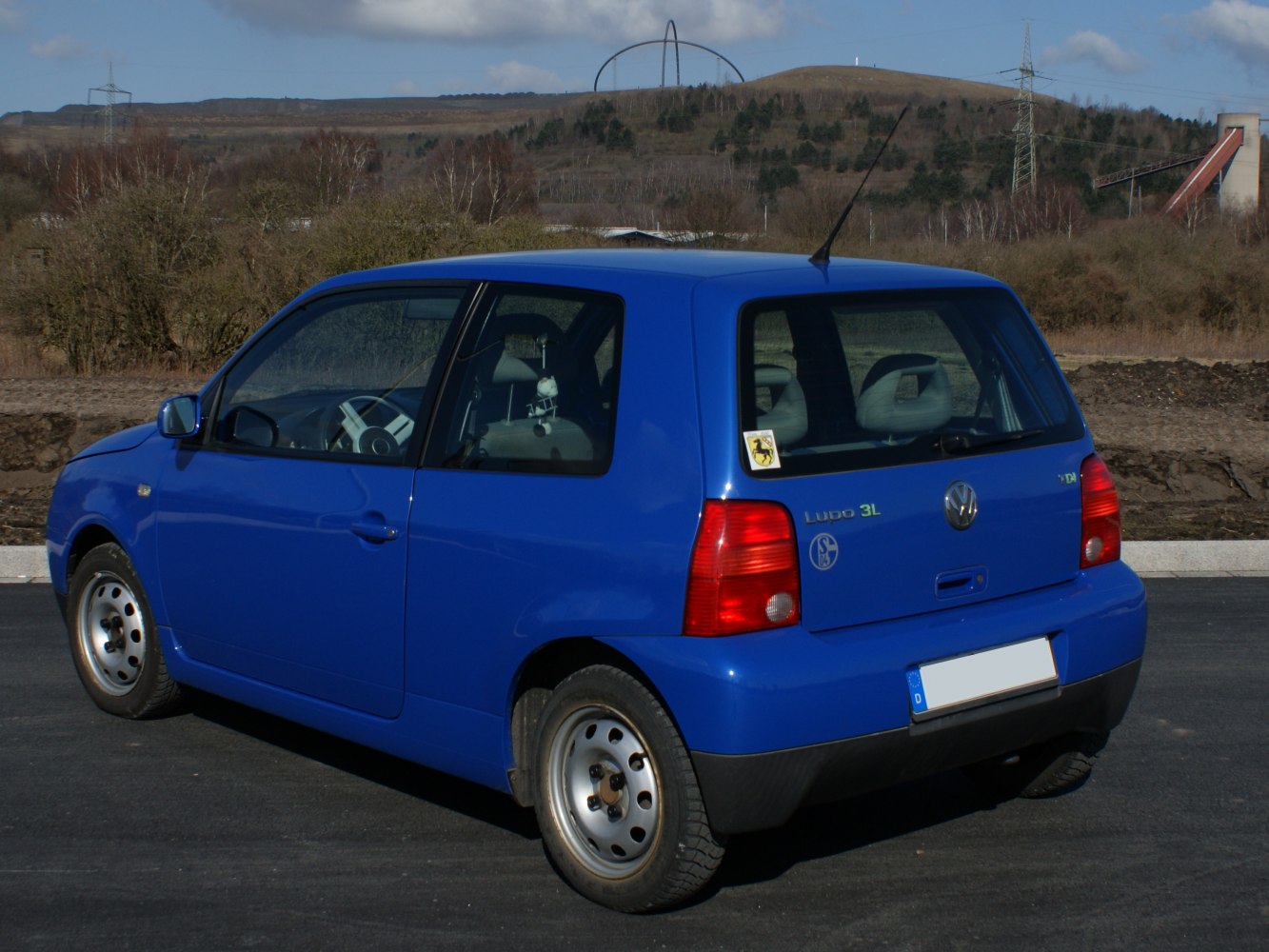Rear side view of a blue 3-door hatchback with steel wheels and antenna