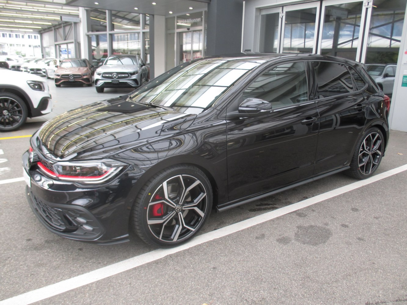 Black hatchback with red accents and stylish alloy wheels
