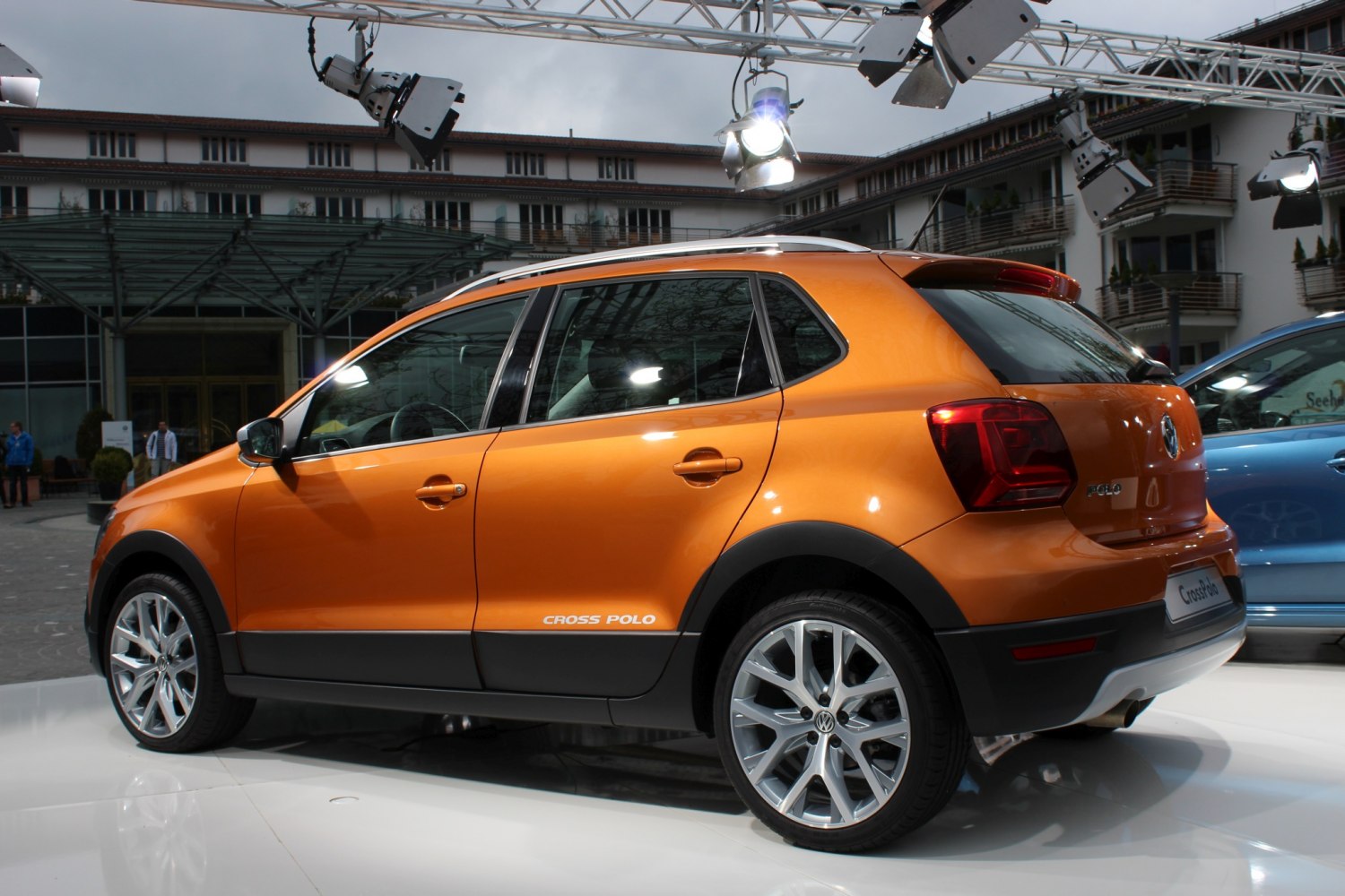 Side profile of an orange compact crossover with alloy wheels and roof rails