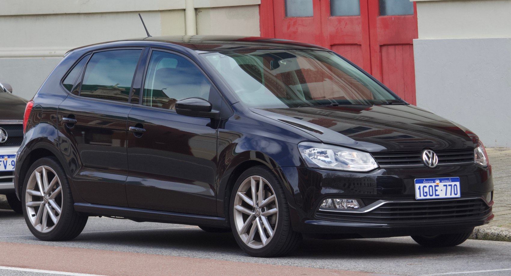 Front side view of black hatchback with alloy wheels and clear headlights.