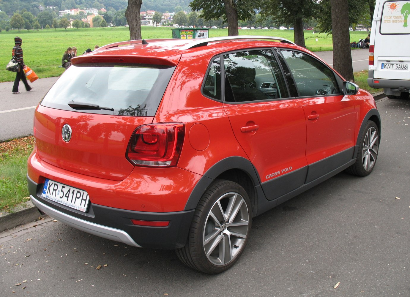 Red hatchback with sporty wheels captured from rear side outdoors
