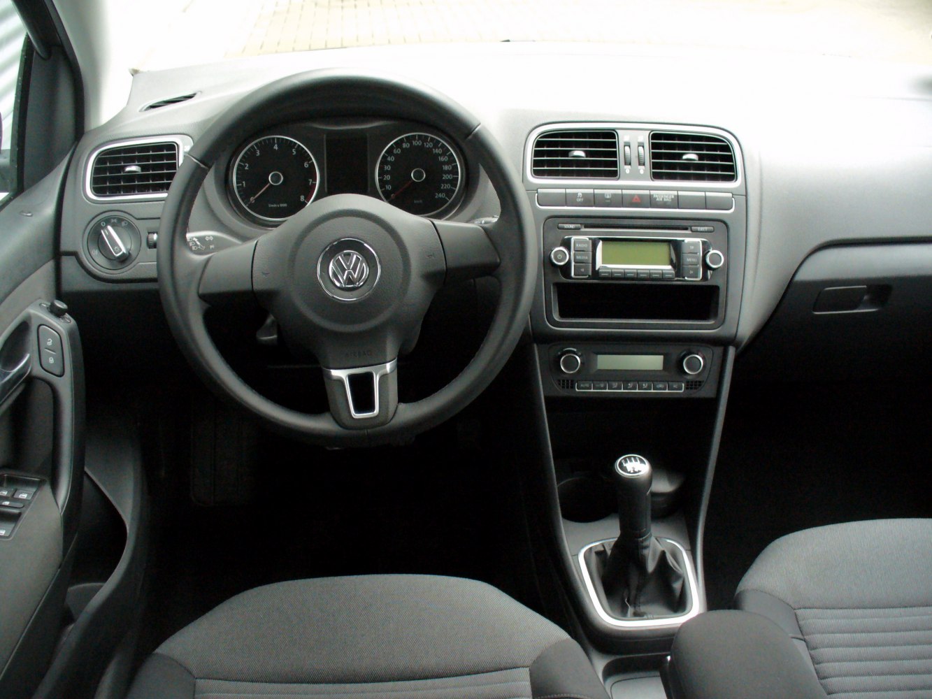 Dashboard, steering wheel, and manual gear shift in compact car interior