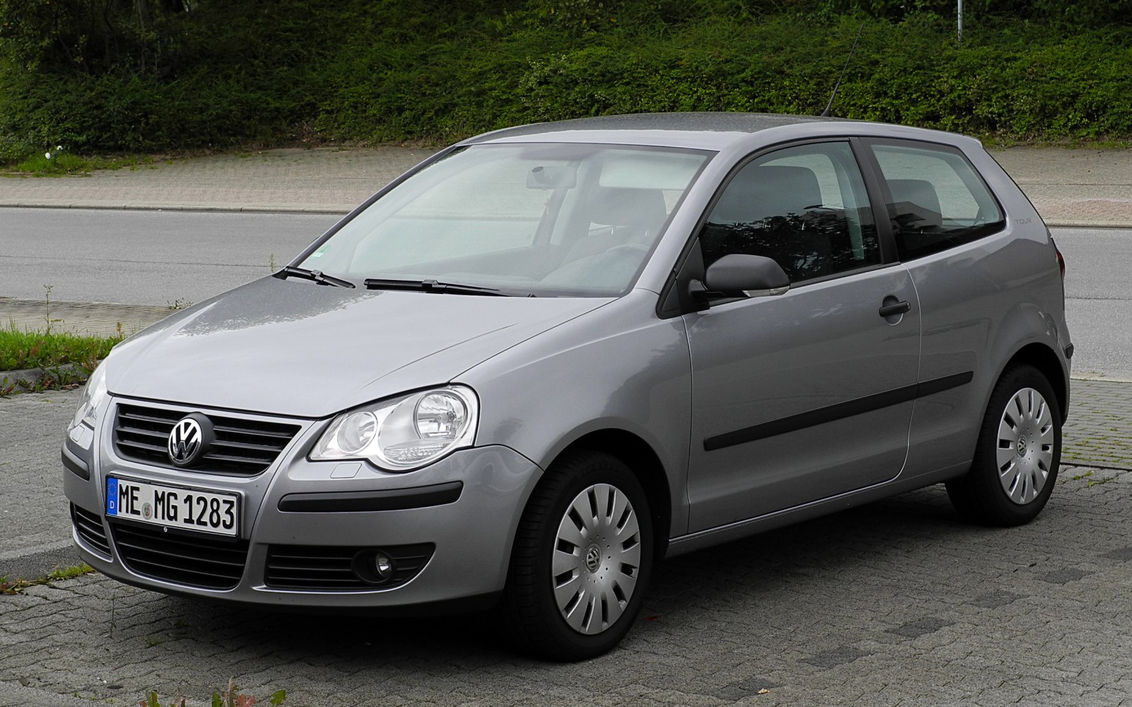 Gray compact hatchback, front-side angle with visible headlights and wheels