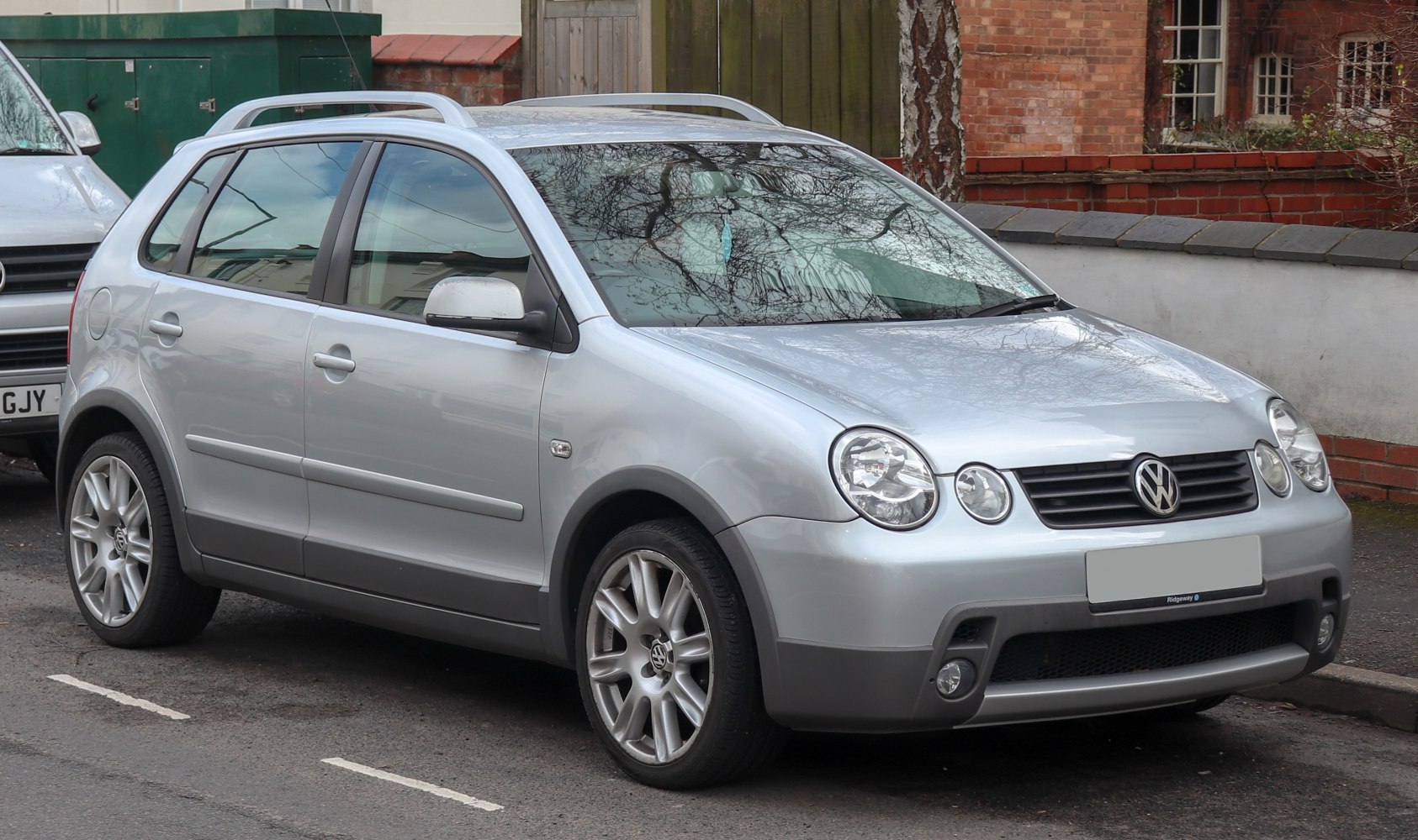 Round dual headlights and roof rails on silver compact hatchback