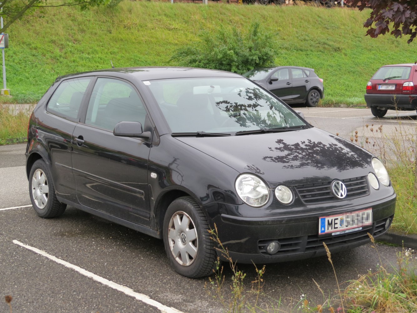 Black compact hatchback with round headlights and front grille.