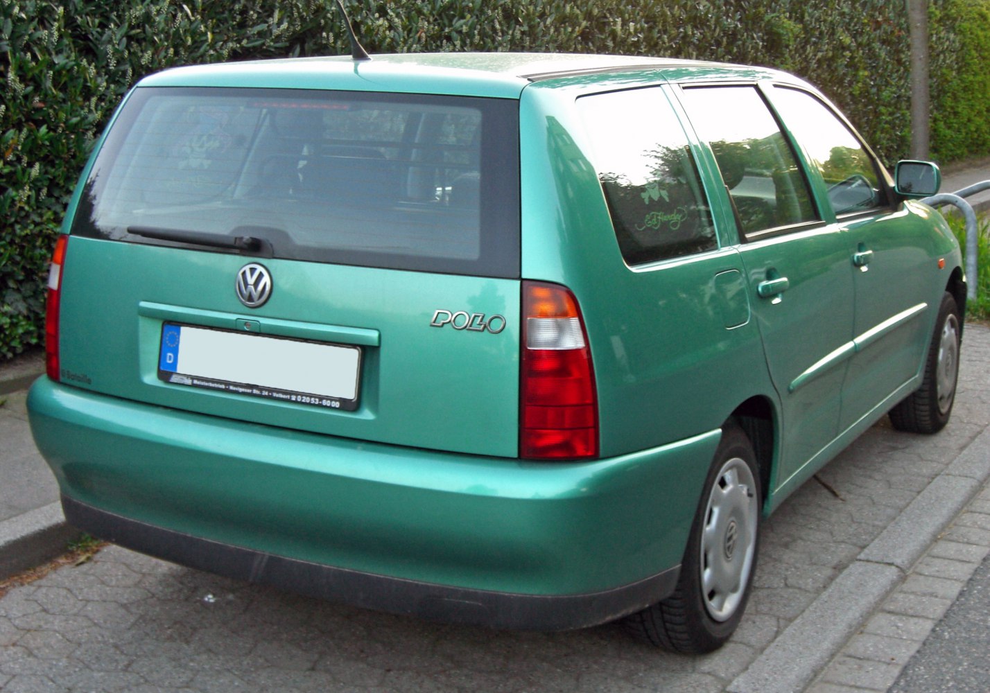 Rear view of a green hatchback with distinct taillights and rear window wiper