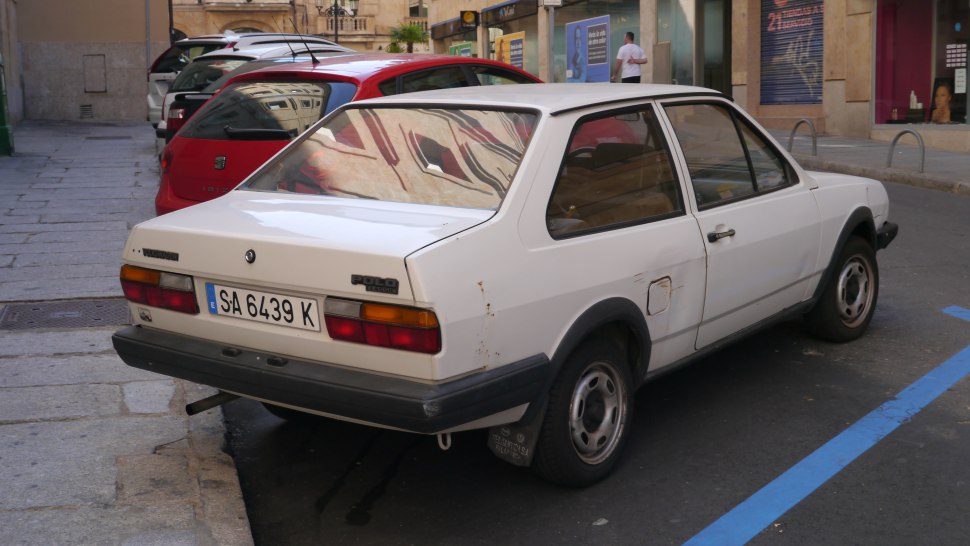 Rear view of classic 1980s white hatchback with rectangular tail lights and steel wheels.