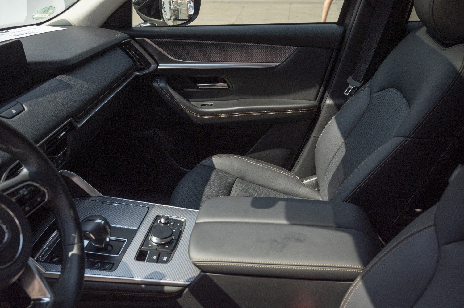 Modern car interior with leather seats, center console, and control dial.