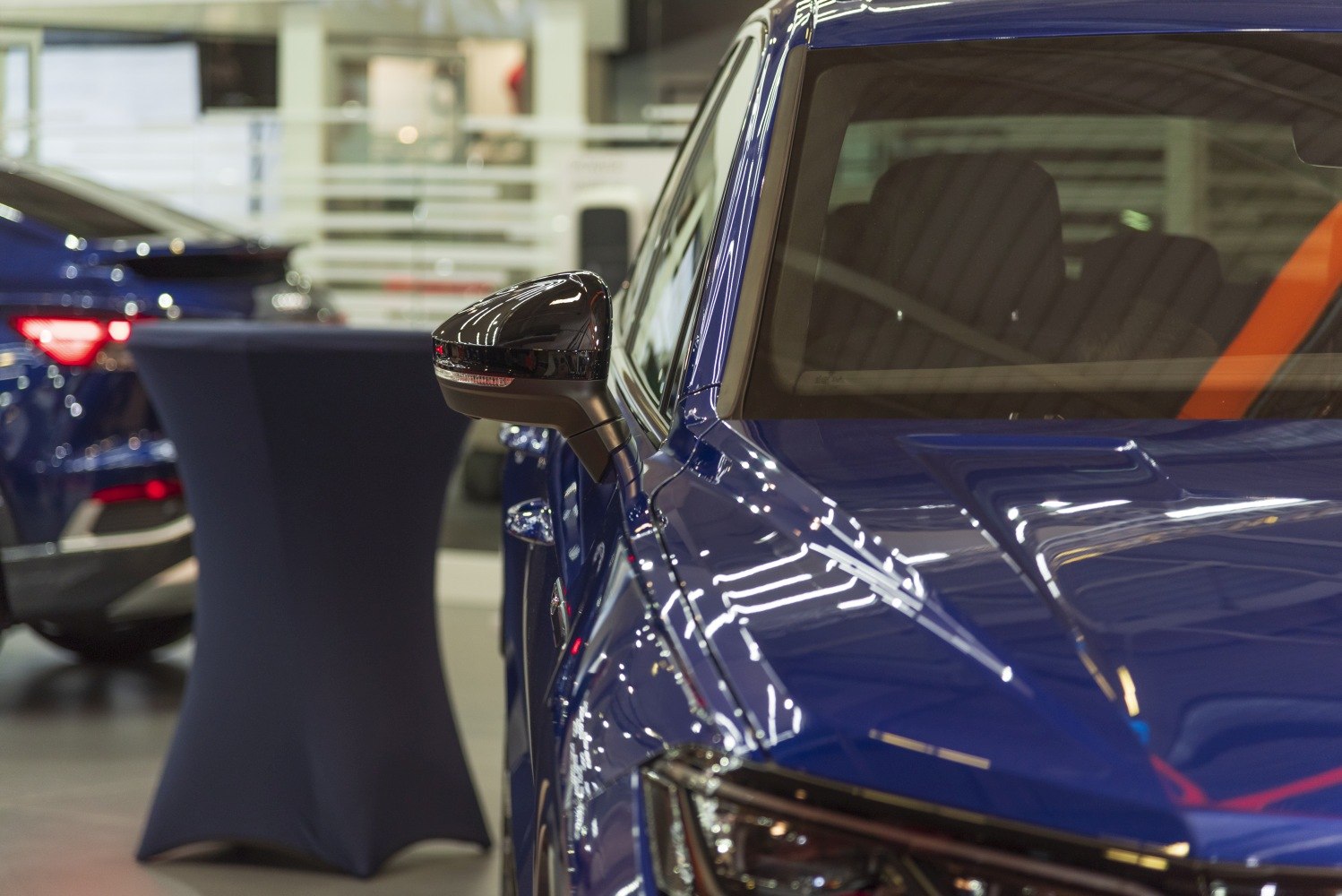 Close-up of side mirror and front windshield with glossy blue finish
