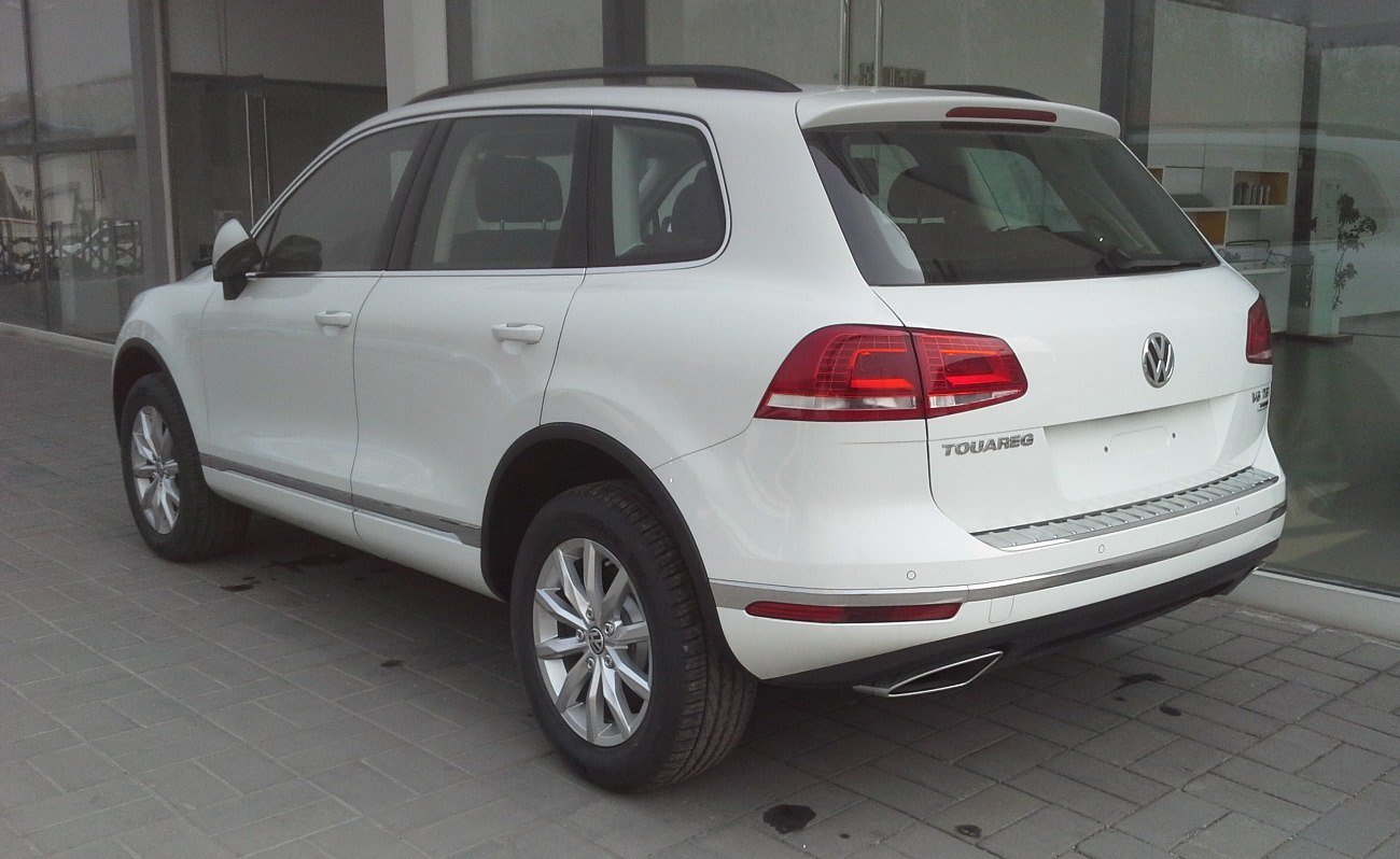 Rear side view of white SUV with tail lights and alloy wheels.