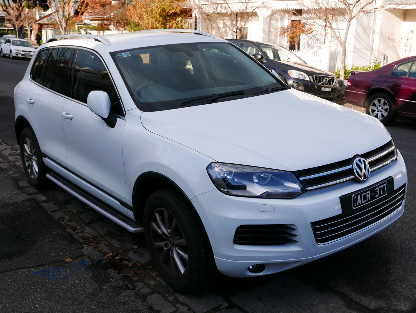 White mid-size SUV with roof rails and side running boards