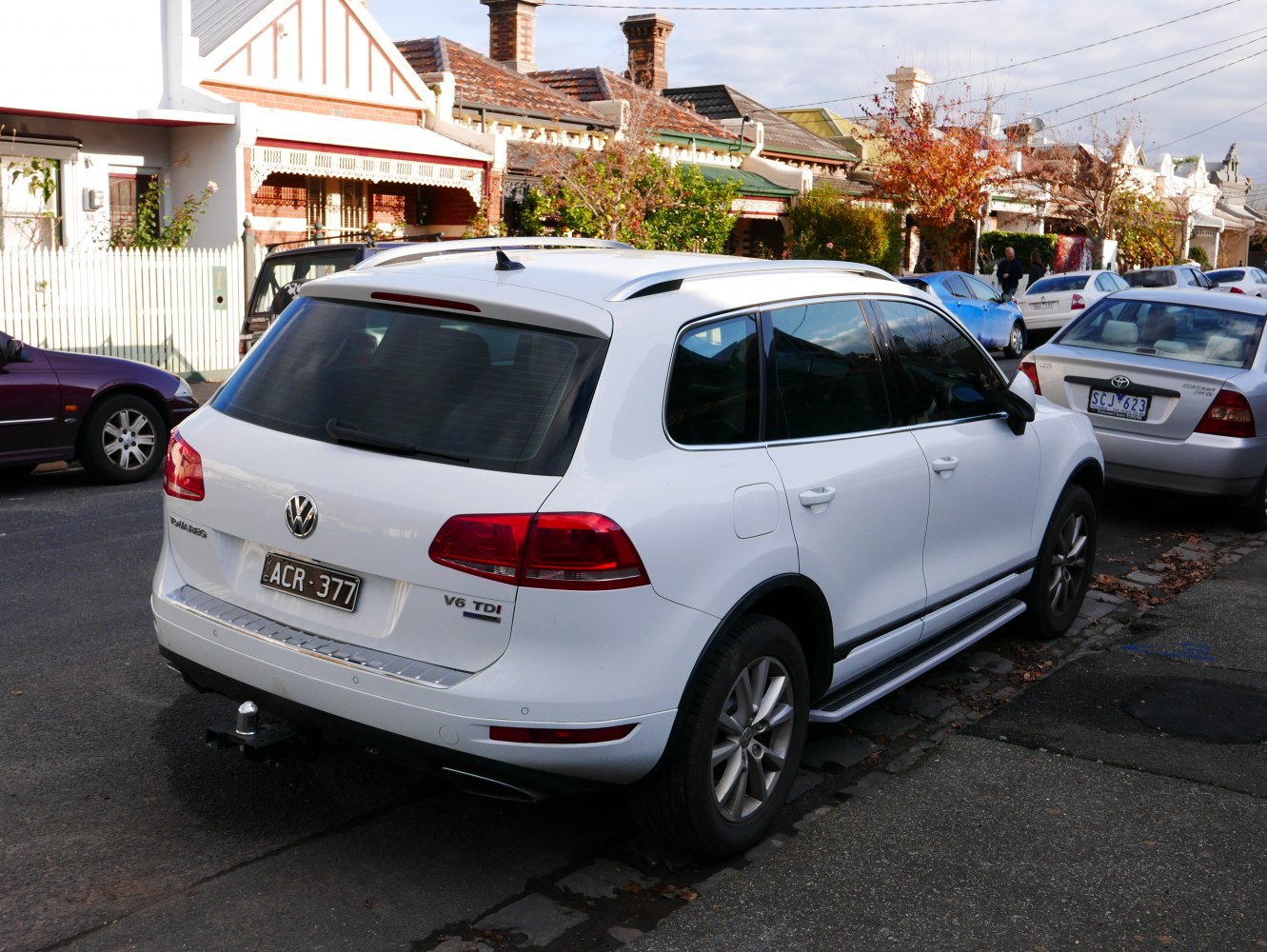 Rear and side view of white SUV with roof rails and tow hitch