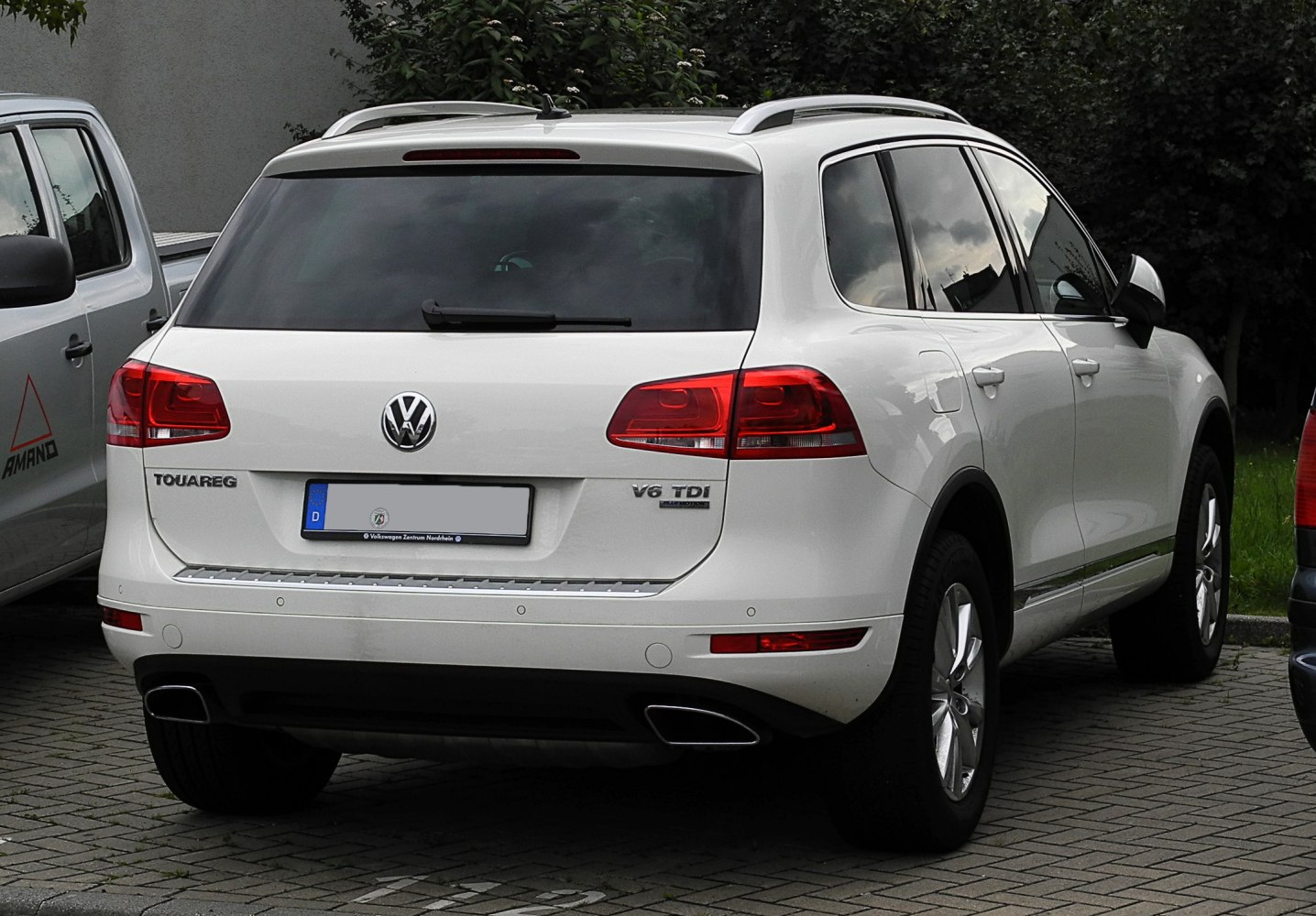 Rear view of white SUV with dual exhaust and roof rails