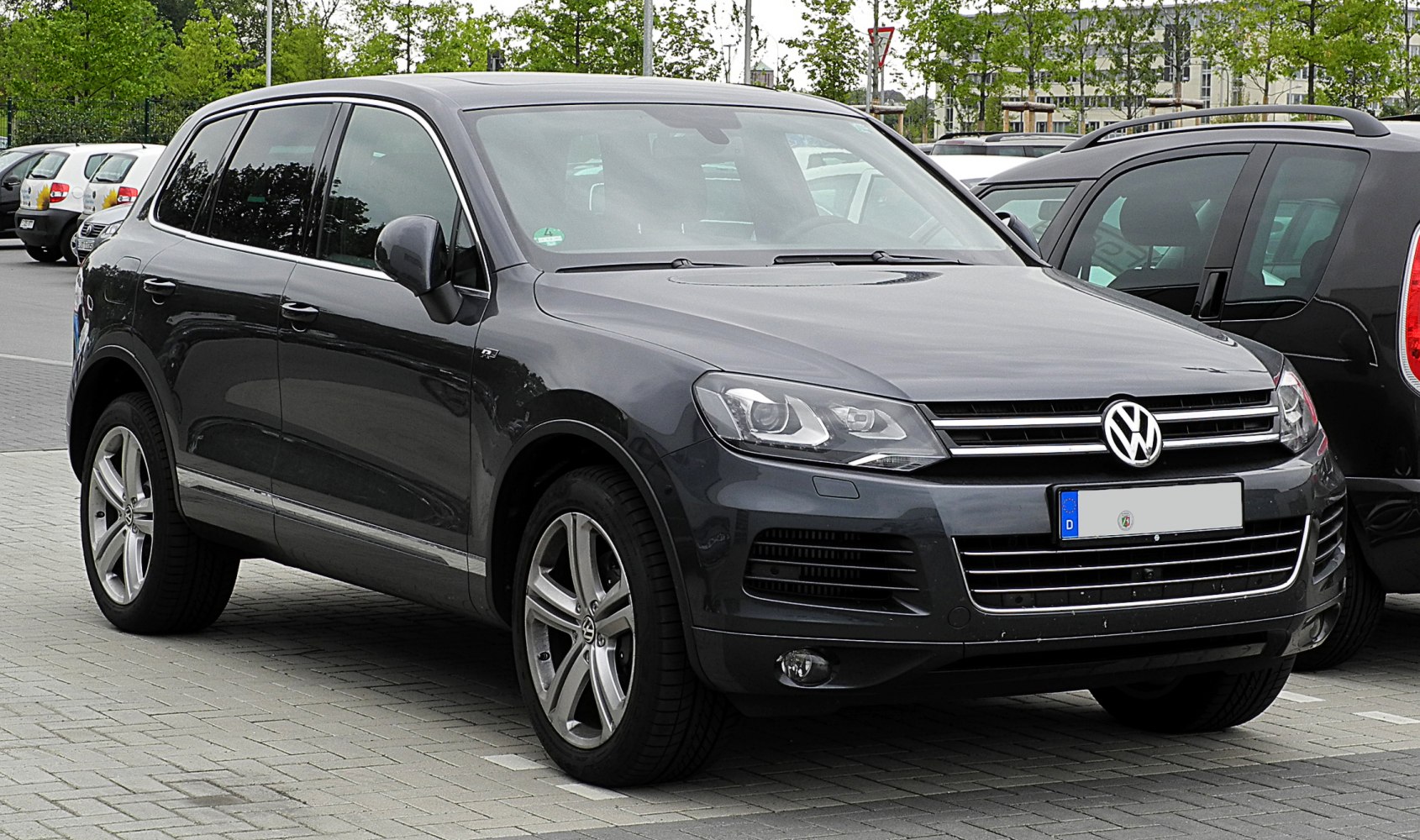 Front side view of dark gray SUV with distinctive headlights and grille.