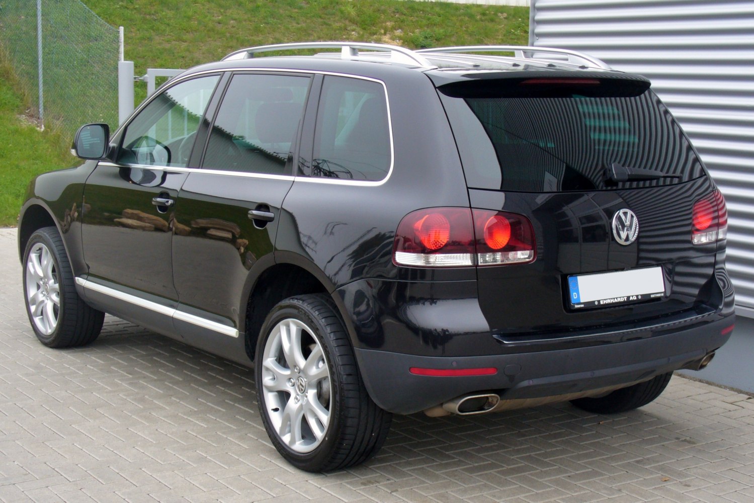 Rear and side view of a black SUV with alloy wheels and dual exhaust.