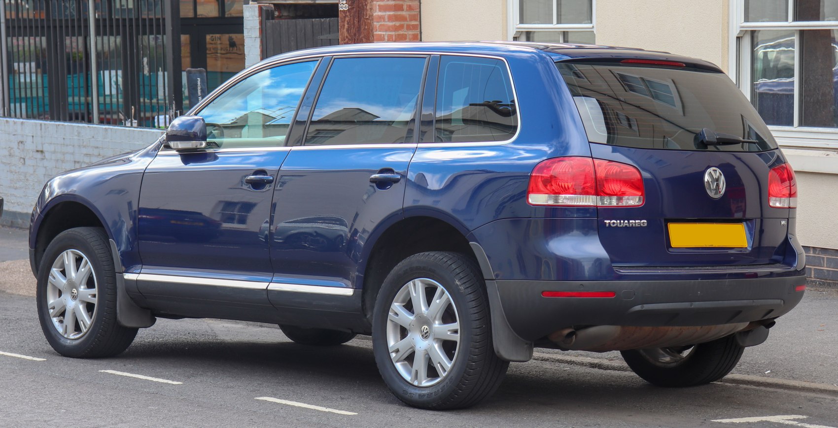 Rear side view of a blue SUV with tinted windows and distinctive taillights