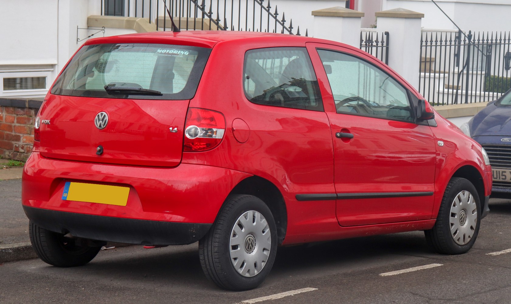 Red 3-door compact hatchback rear side with visible rear lights and hubcaps