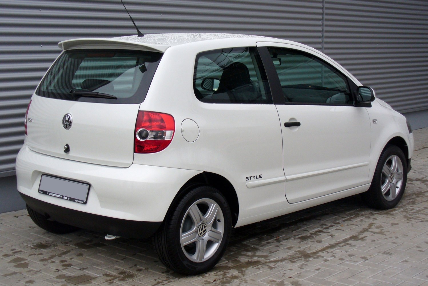 Rear side view of compact 3-door hatchback with roof spoiler and alloy wheels