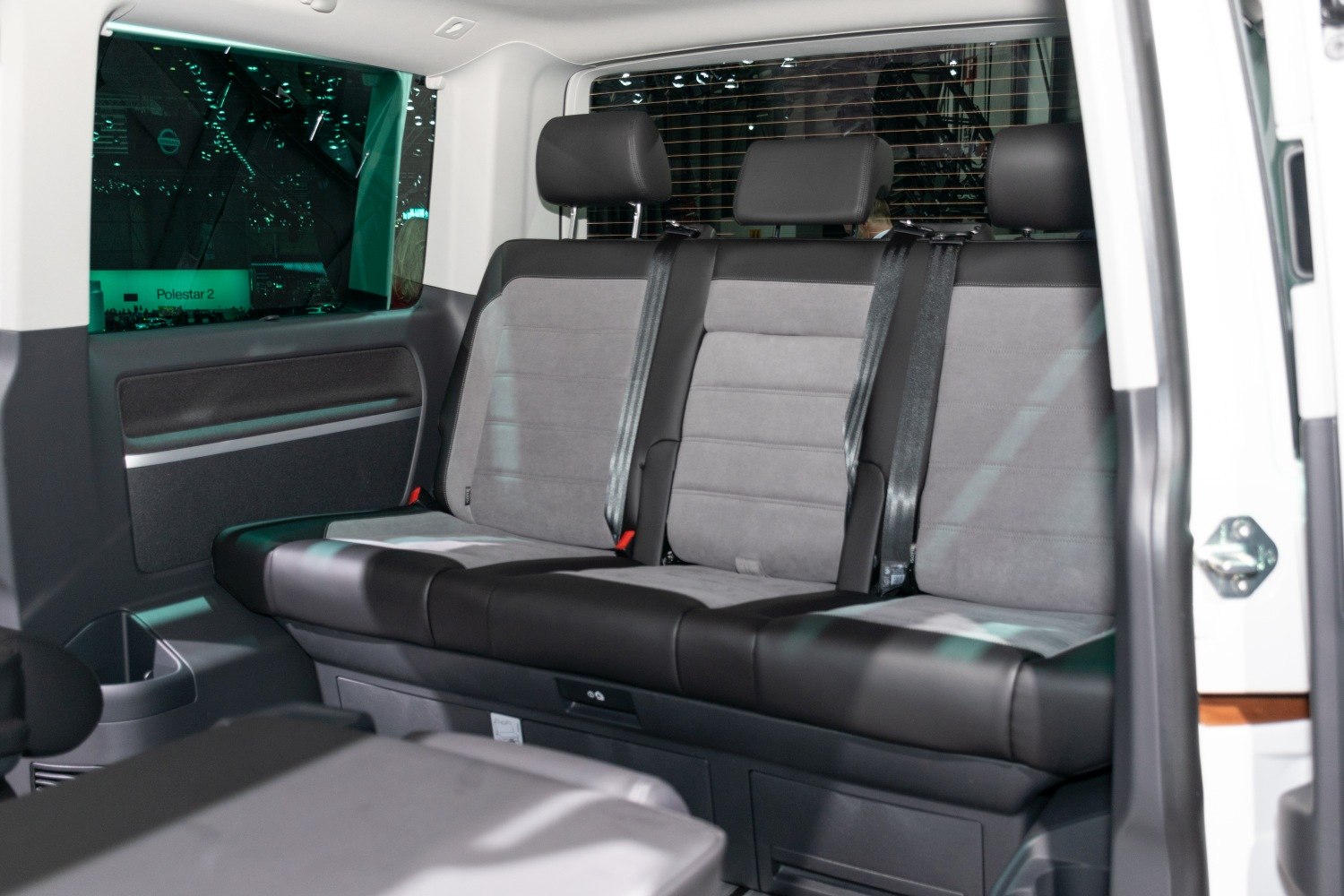 Spacious rear seating with three headrests and seatbelts inside a vehicle.