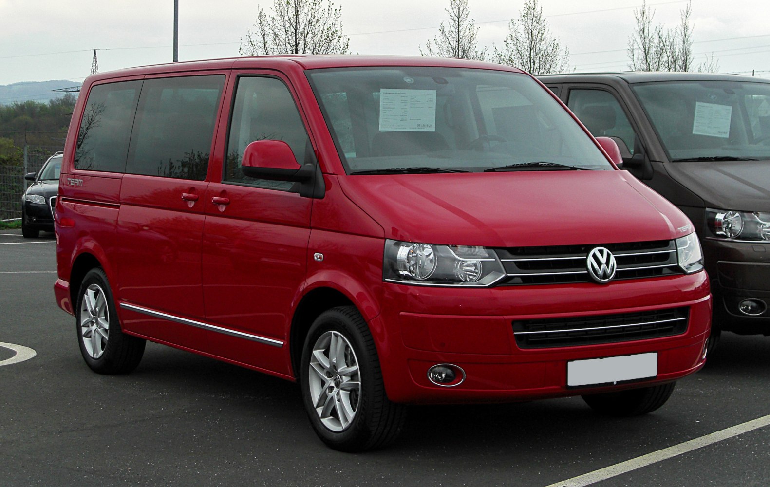 Red minivan front-side view with alloy wheels and large windows